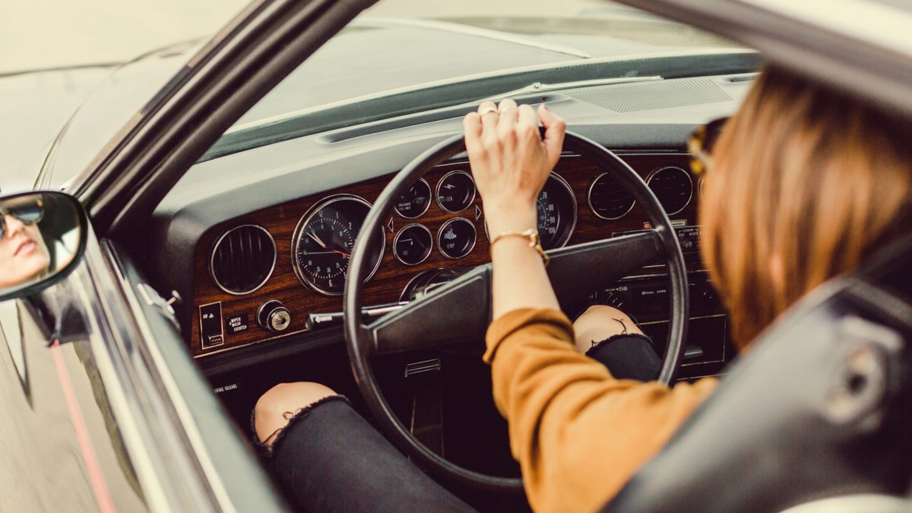 A woman sits in a car holding the steering wheel