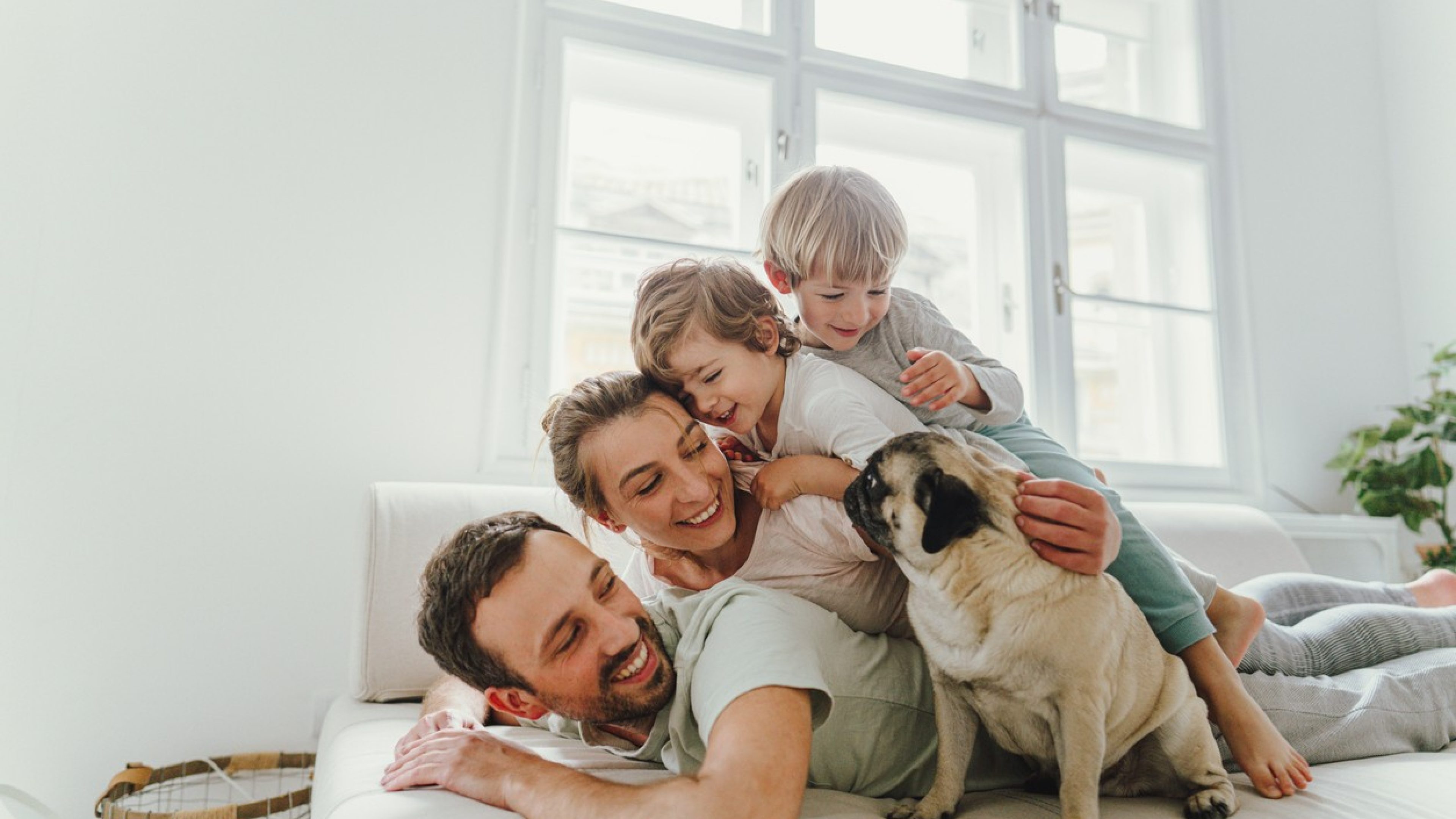 Padre, madre e figli accatastati sul divano, con accanto un cane