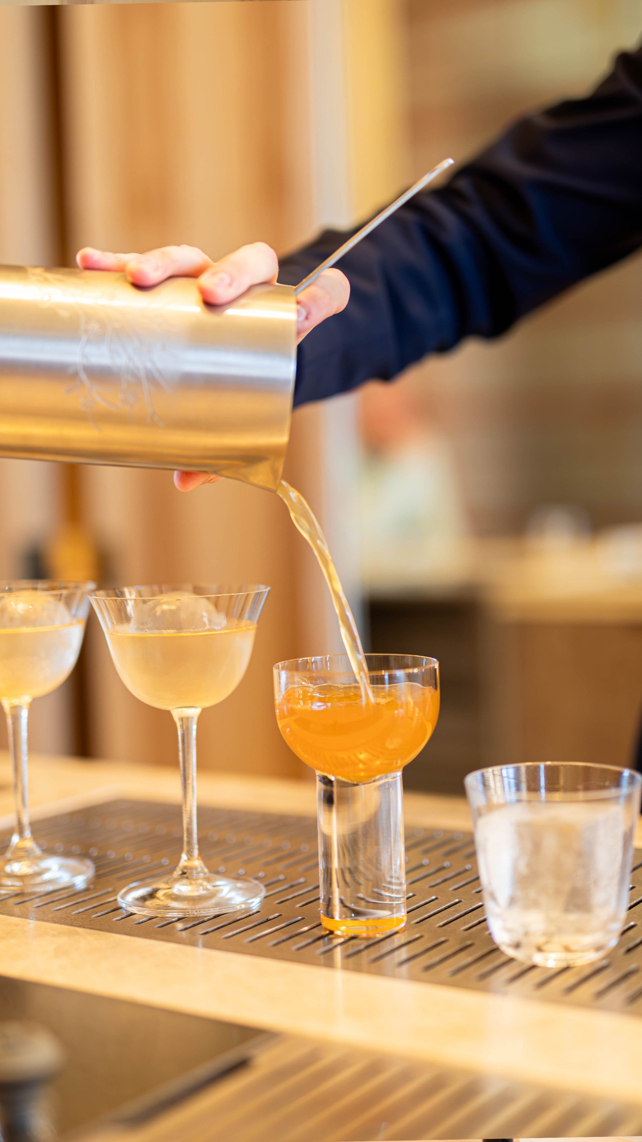 Hand giesst alkoholfreien Drink aus Mischbecher in ein Glas.
