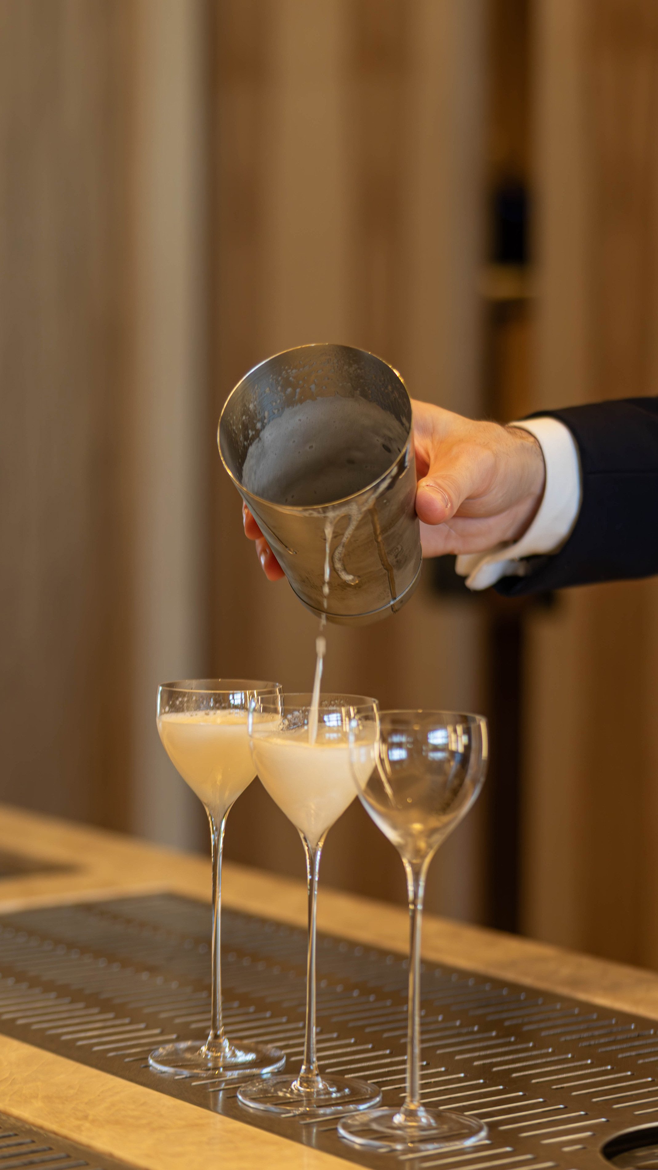 Hand giesst alkoholfreien Drink aus Mischbecher in ein Glas.