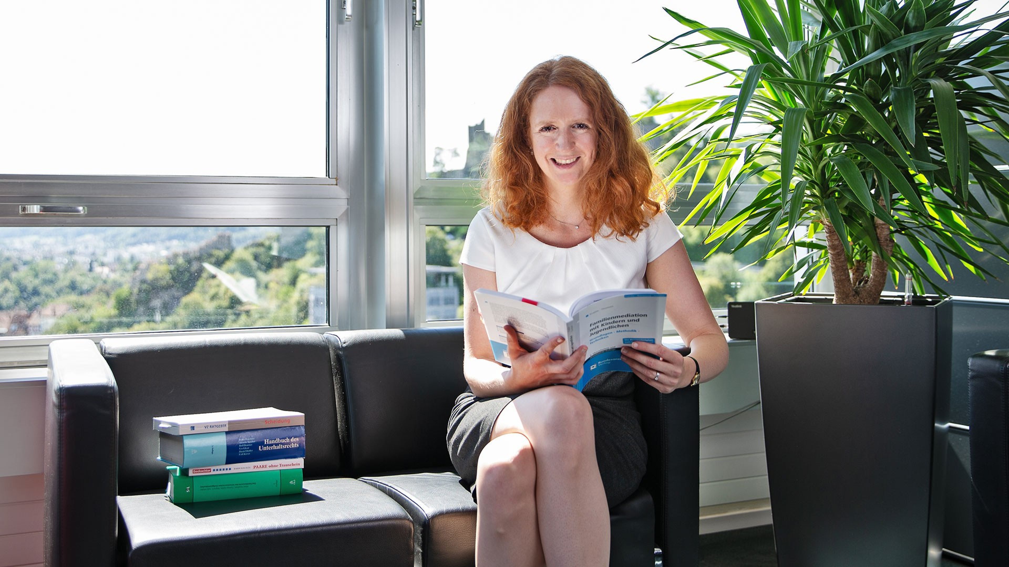 Eliane Benjamin sitzt auf einem Sofa und liest ein Buch