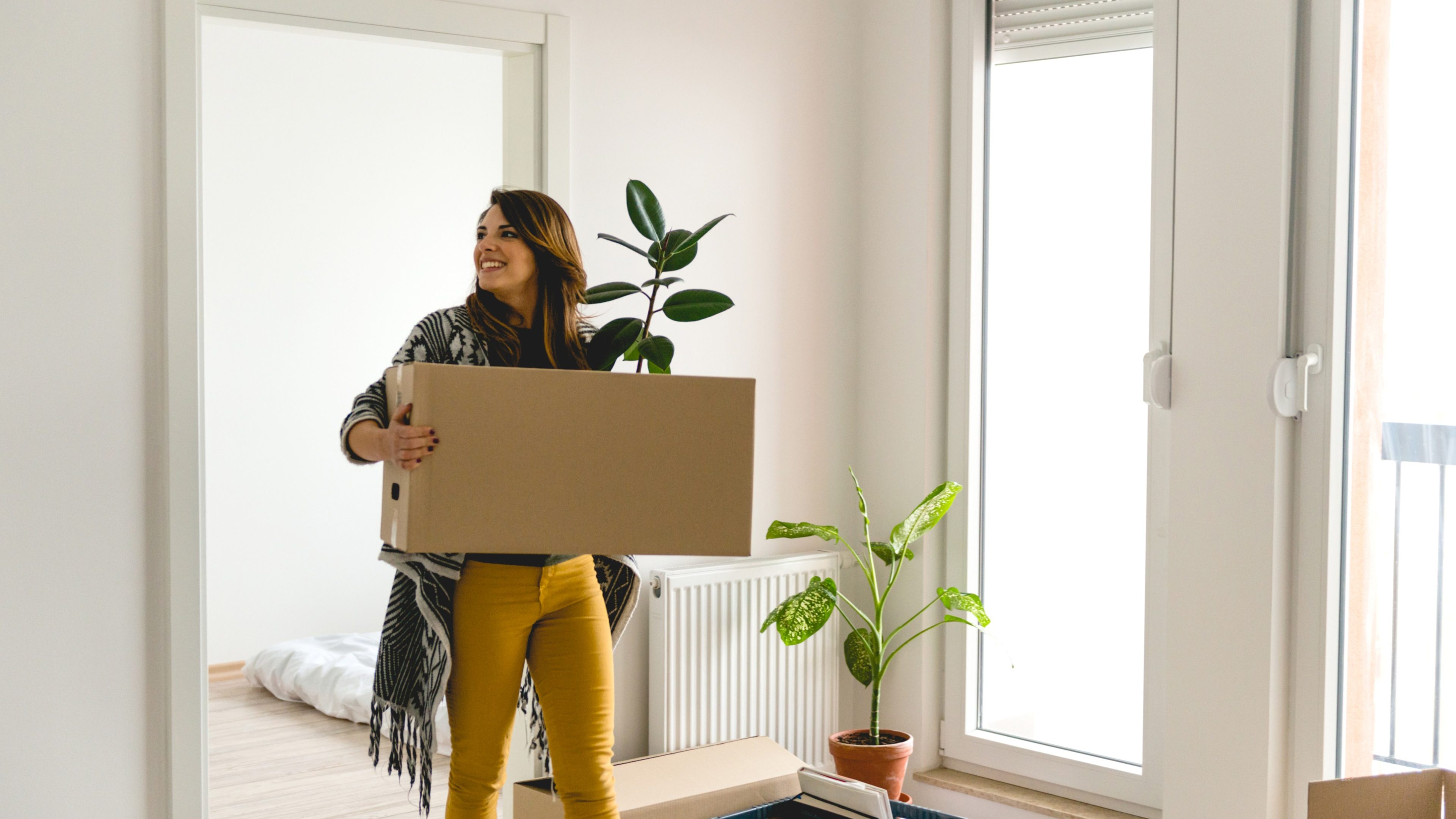 Eine Frau packt Kisten in ihrer ersten eigenen Wohnung aus.