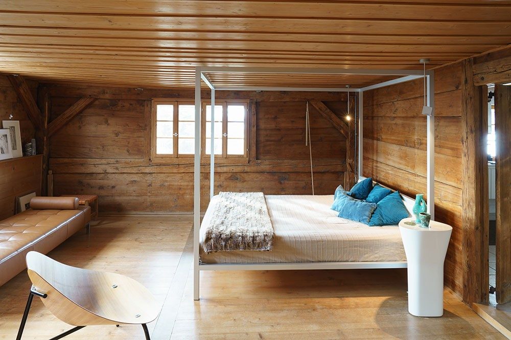 Ein Himmelbett steht in einem Schlafzimmer mit hölzernen Wänden.