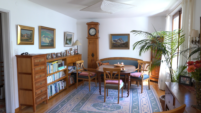 Ein Esszimmer, das mit vielen Möbeln aus Holz und einem Teppich eingerichtet ist.