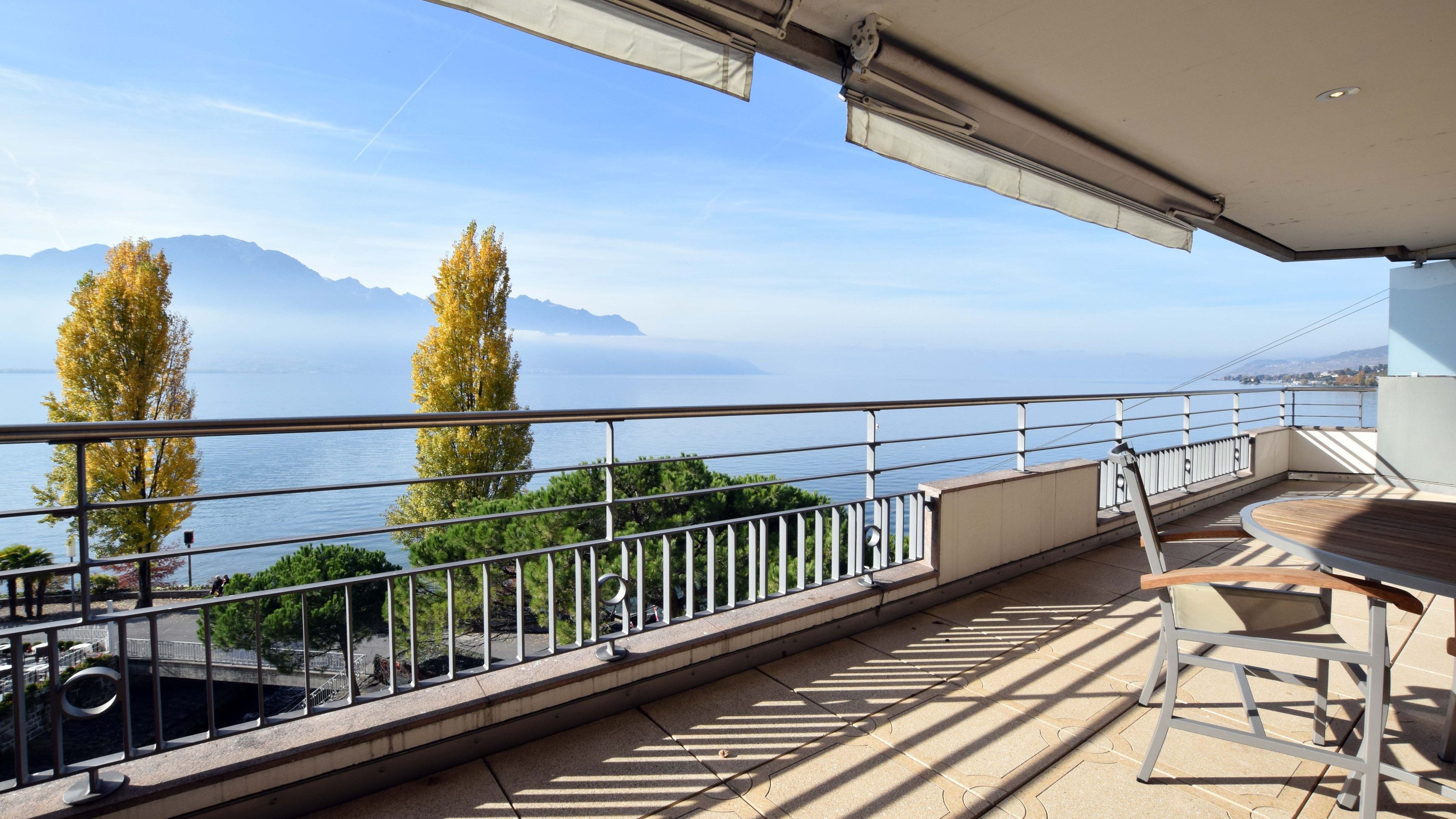 Blick von einem Balkon über den See und auf Hügellandschaft