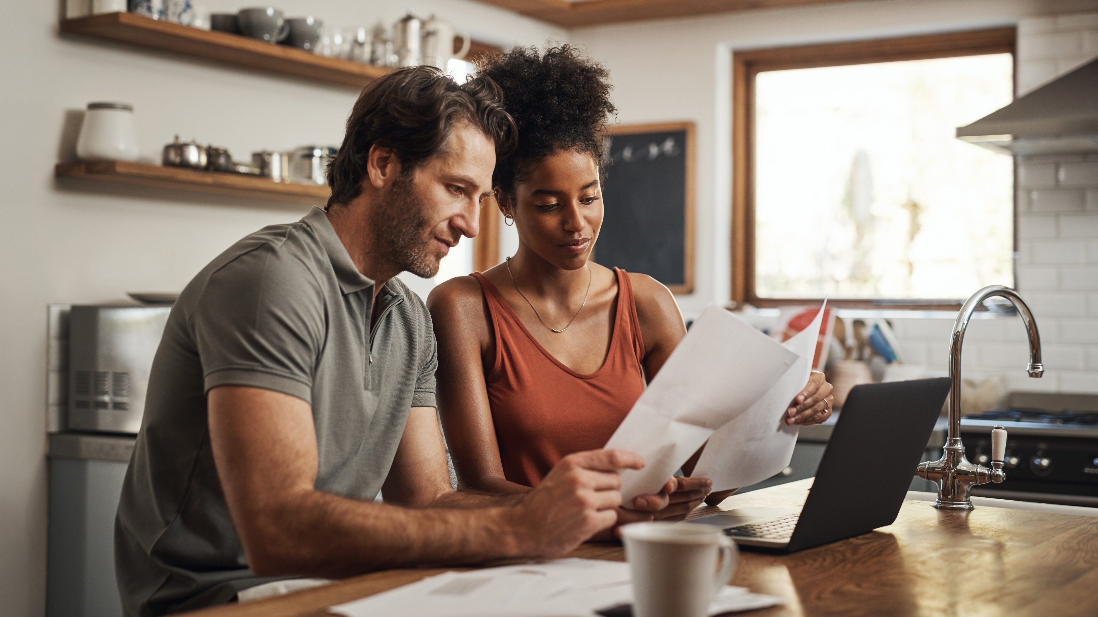 Cropped shot of a couple using their laptop and going through paperwork at home