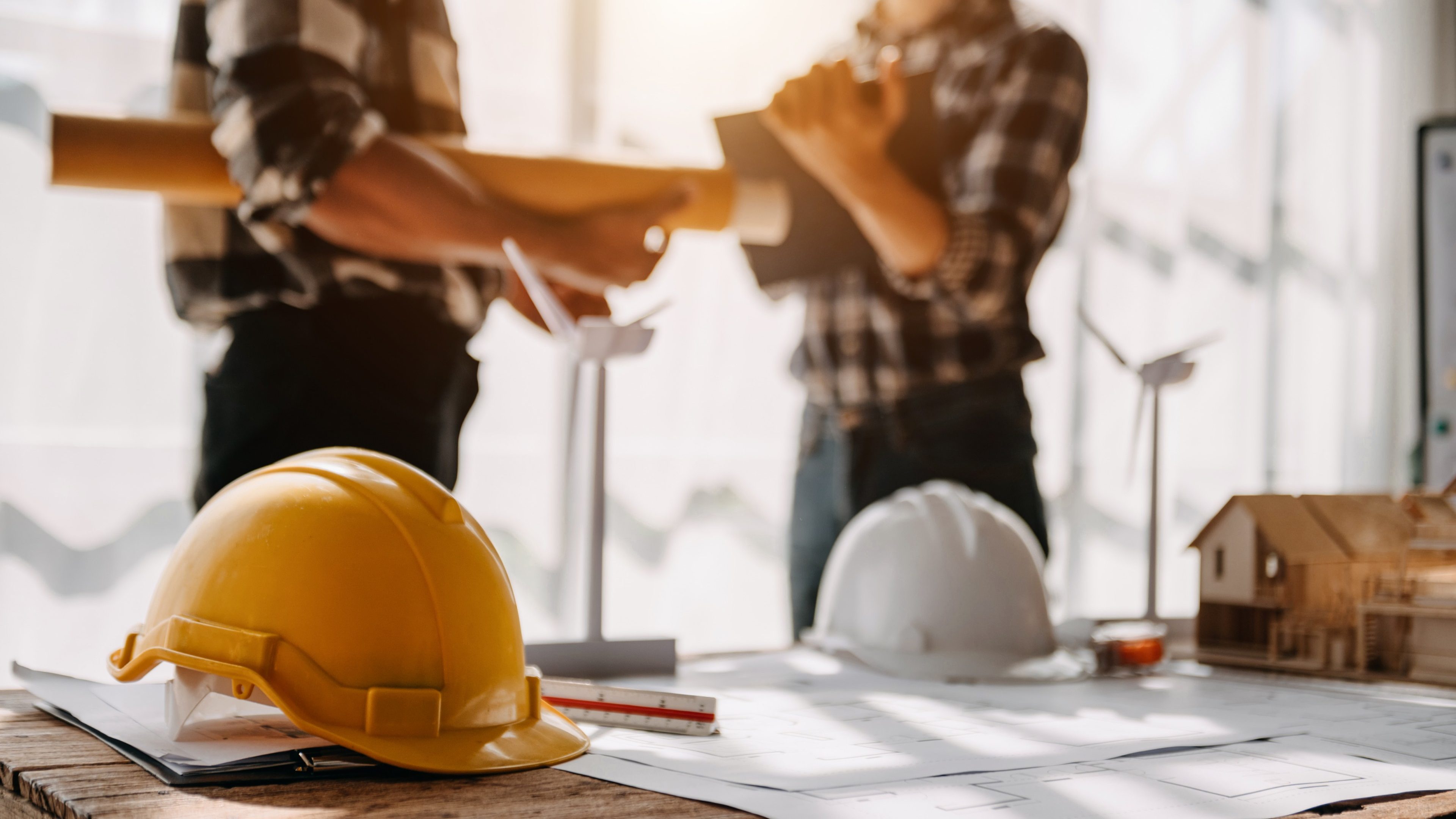 Construction team shake hands greeting start new project plan behind yellow helmet on desk in office center to consults about their building project.
