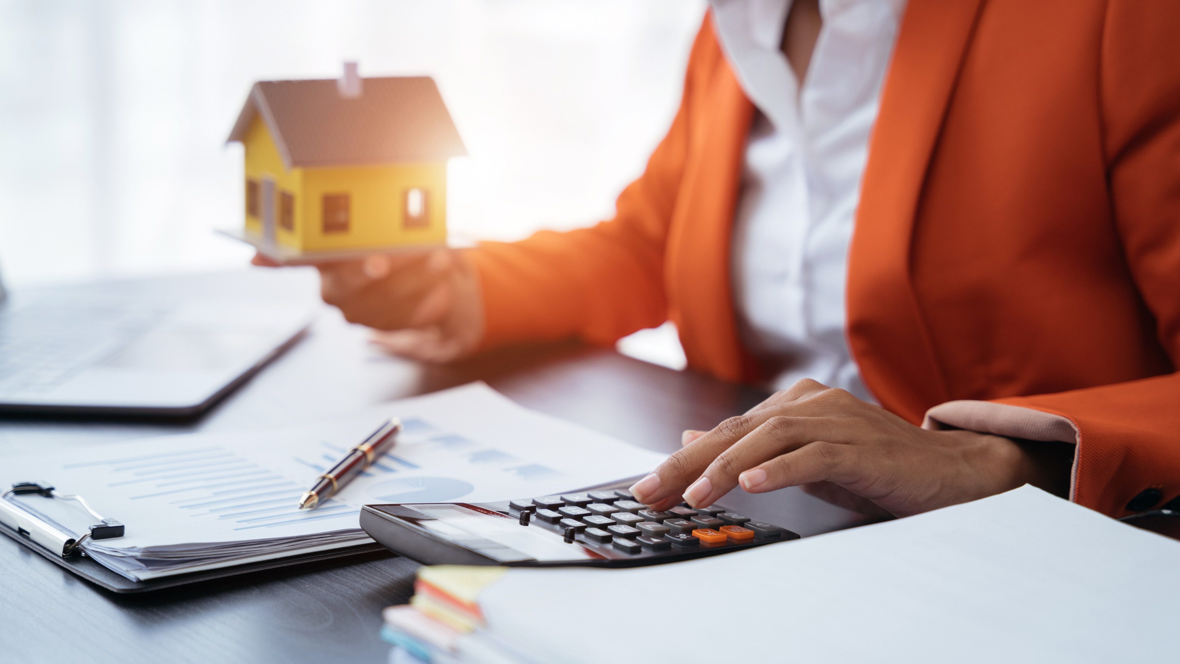 home loan officer uses a calculator with a house plan.