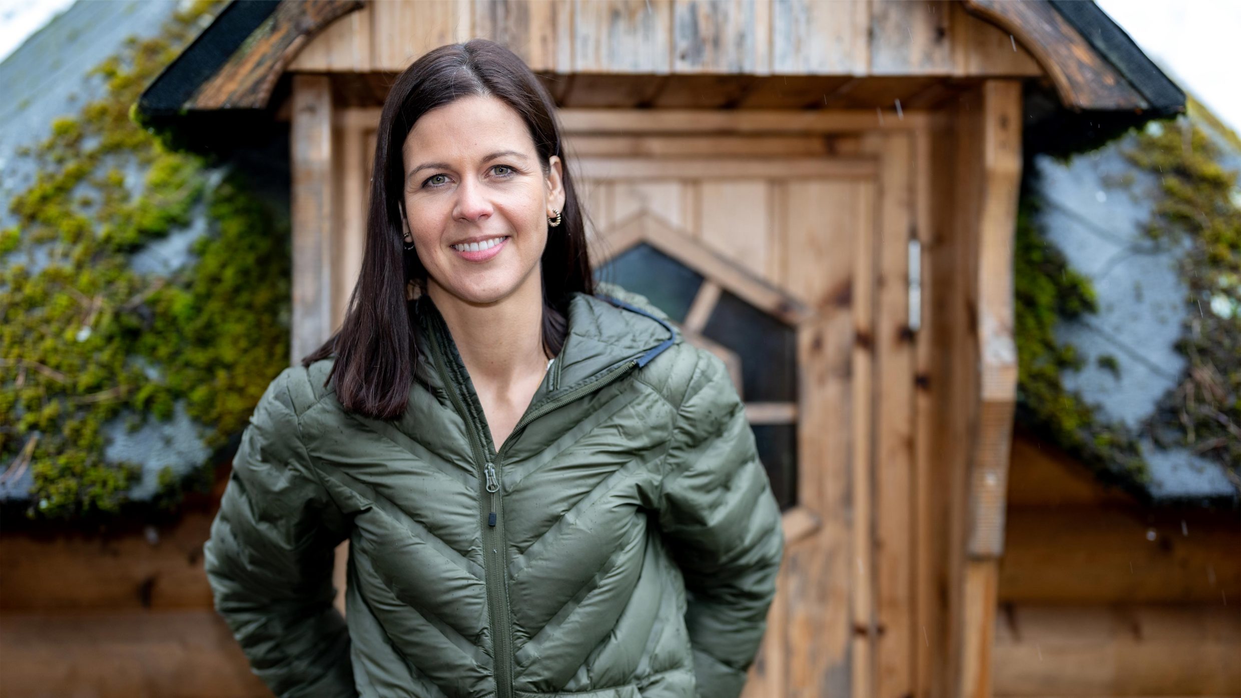 Lächelnde Frau steht vor einer Hütte