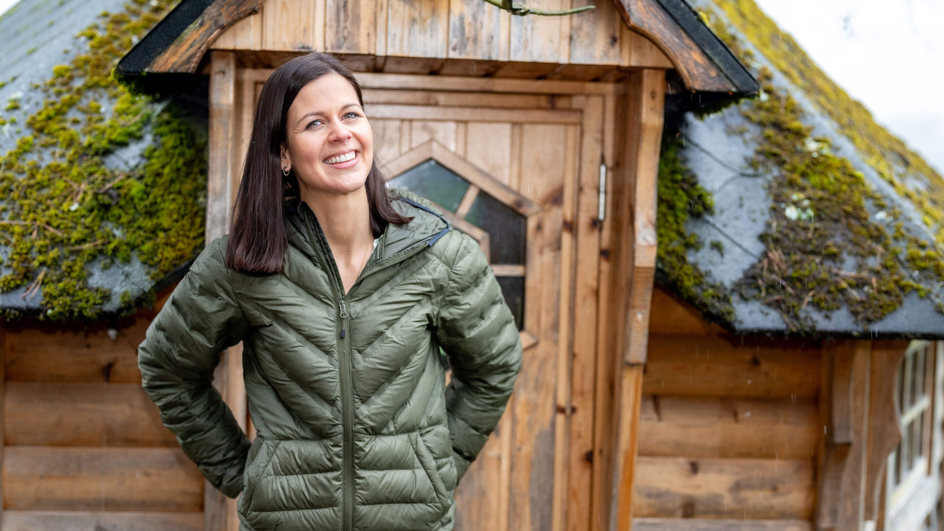 Lächelnde Frau steht vor einer Hütte