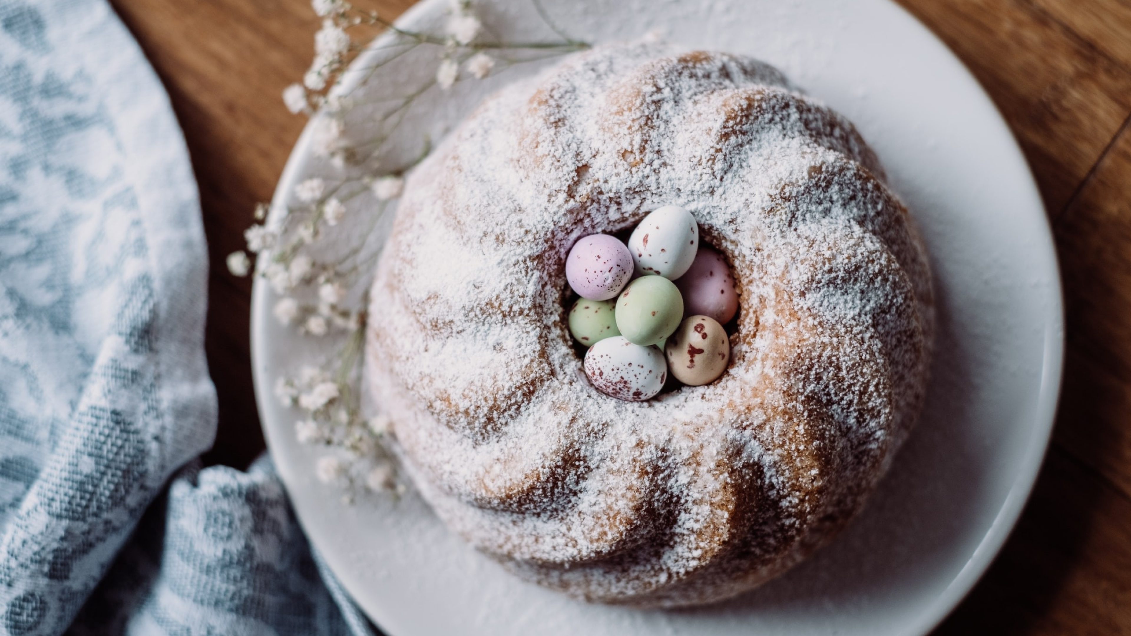 Ein runder Kuchen mit Puderzucker garniert, in der Kuchenmitte sind kleine Ostereier drapiert.