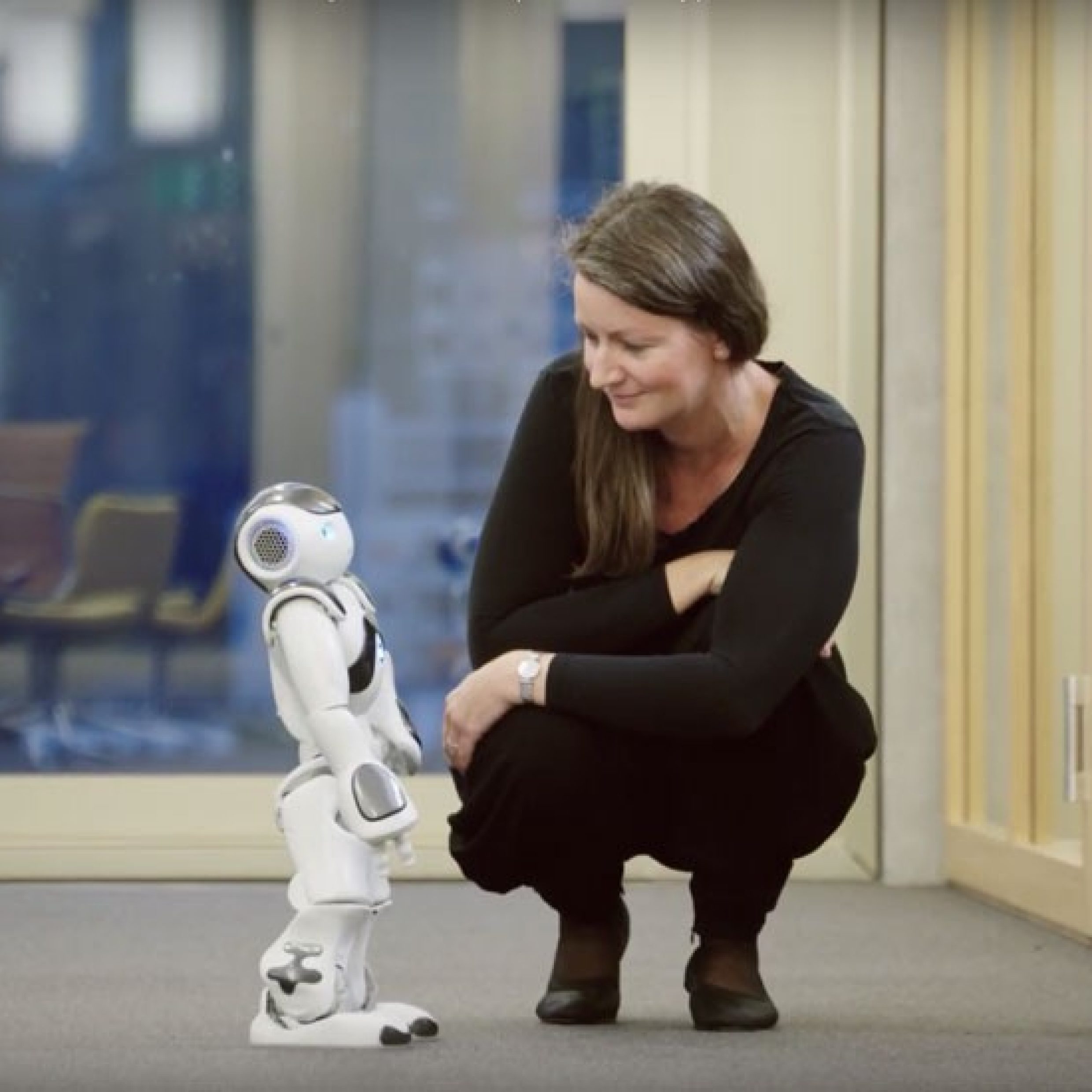 Prof. Dr. Misoch sitzt neben Roboter, der das Altern der Menschen verändern wird.