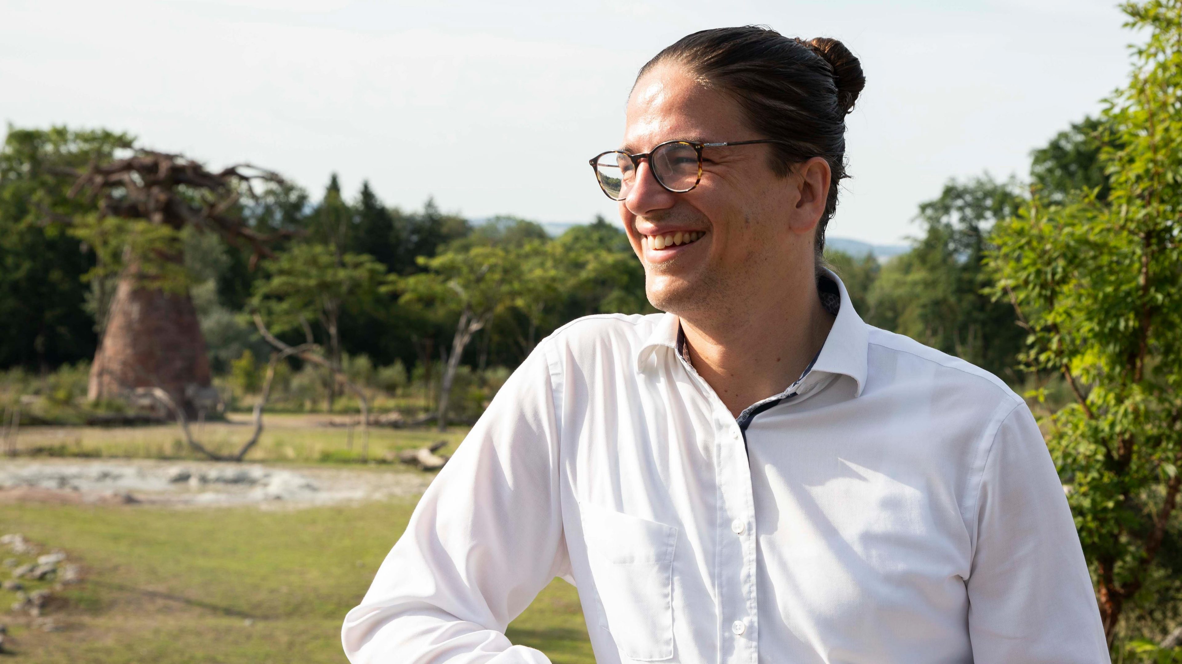 Portrait von einem lächelnden Mann mit Brille, der in die Weite schaut