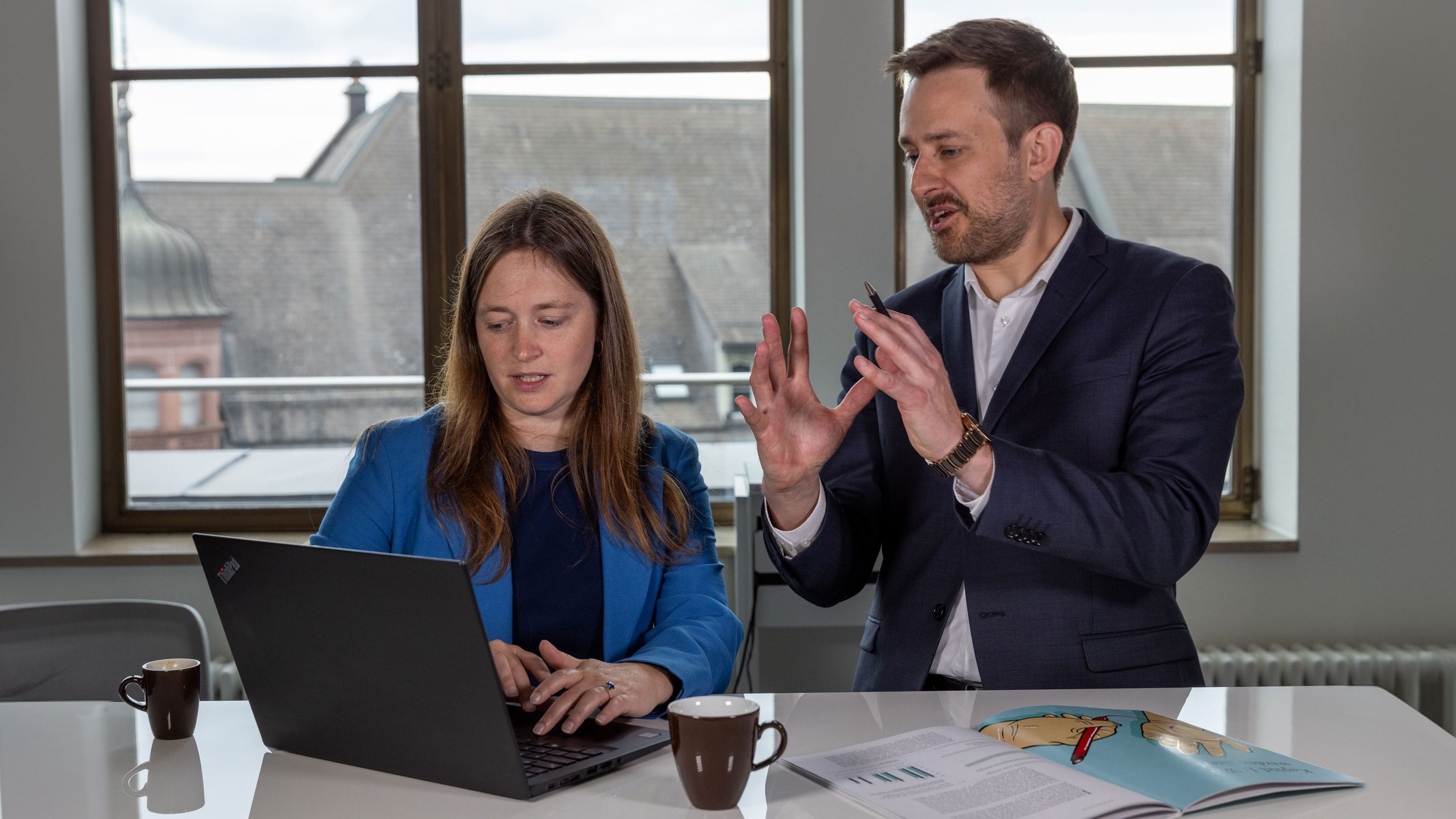 Fotografie Mann und Frau besprechen sich vor geöffnetem Laptop 