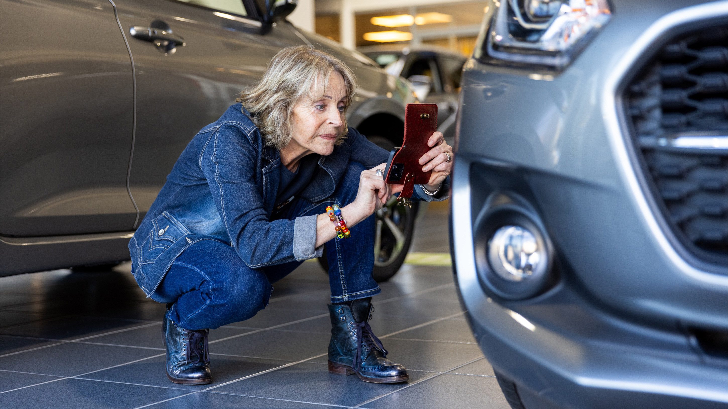 Frau in der Hocke fotografiert Auto in Autogarage