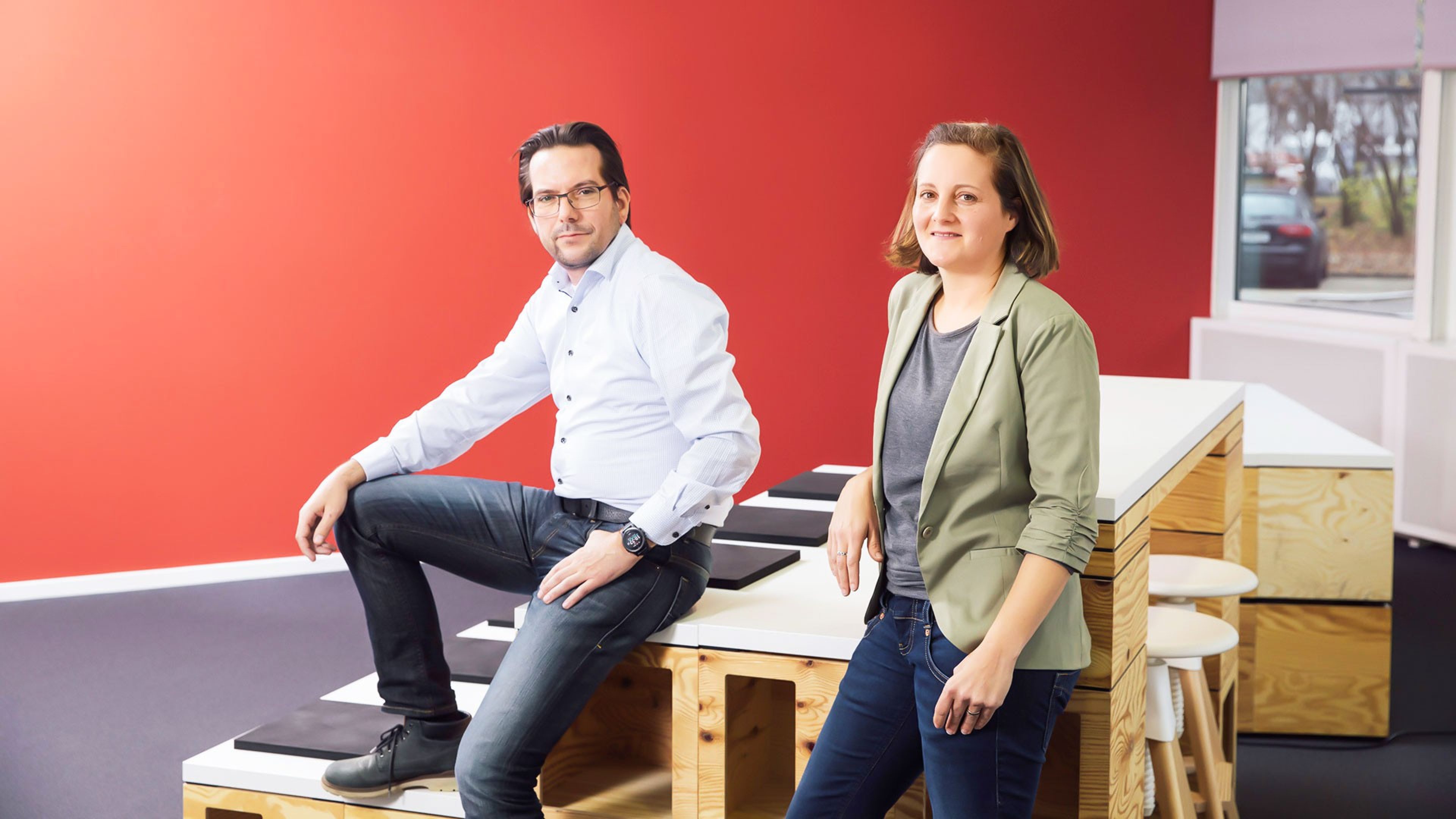 Die beiden Teamleiter sitzen auf einem Tisch im Swiss Life-Gebäude.