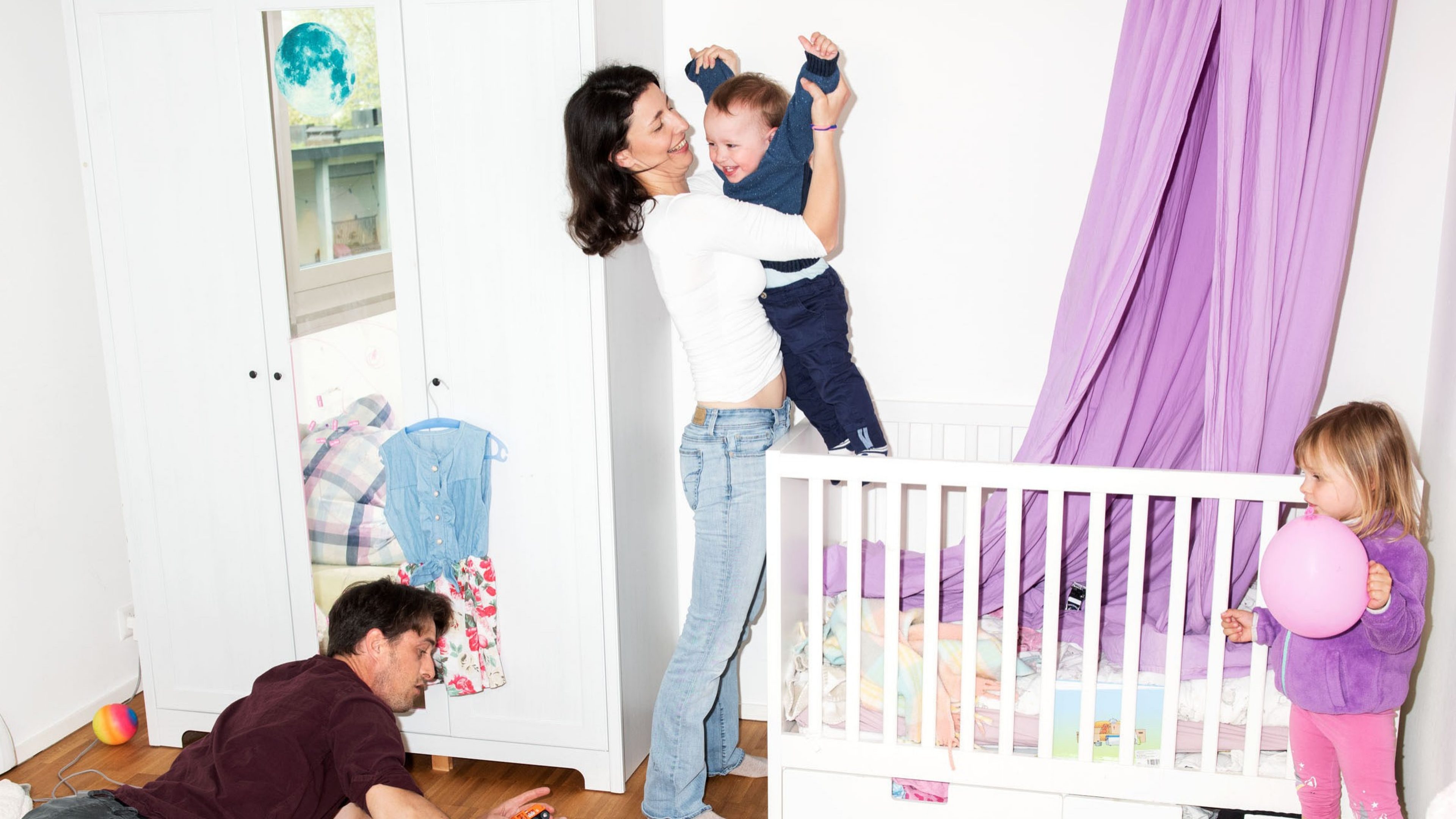 Eltern spielen mit ihren zwei Kindern im Kinderzimmer.