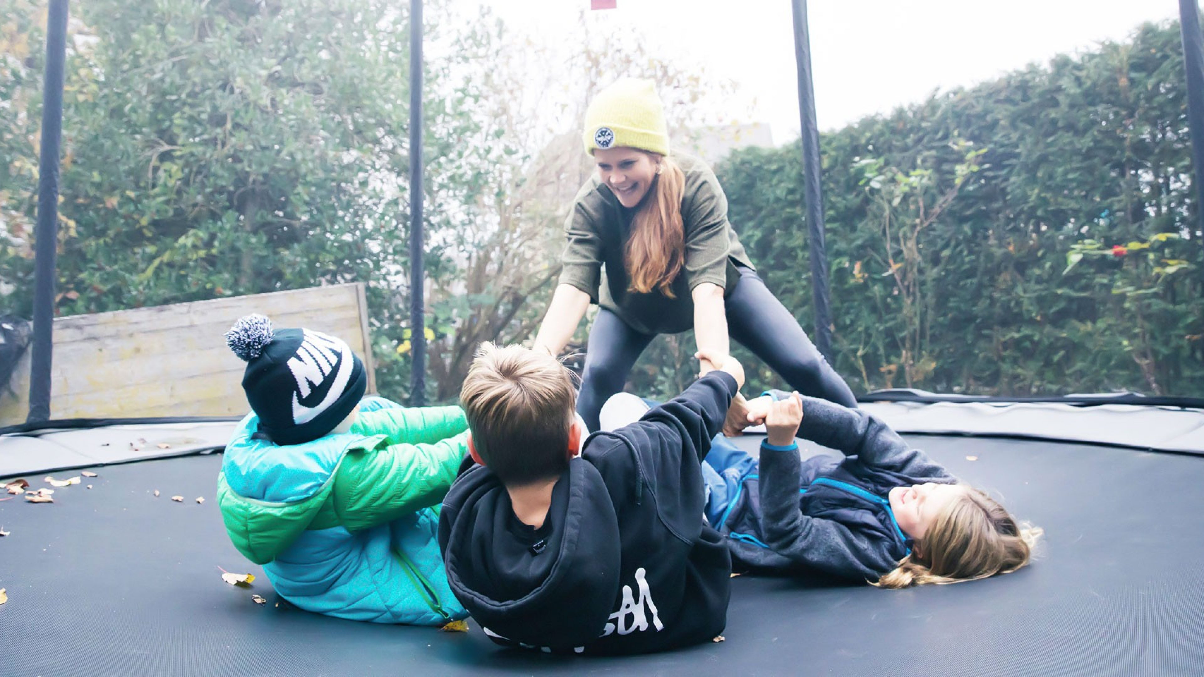 Melanie Gujan spielt mit ihren drei Kindern zuhause auf einem Trampolin. 