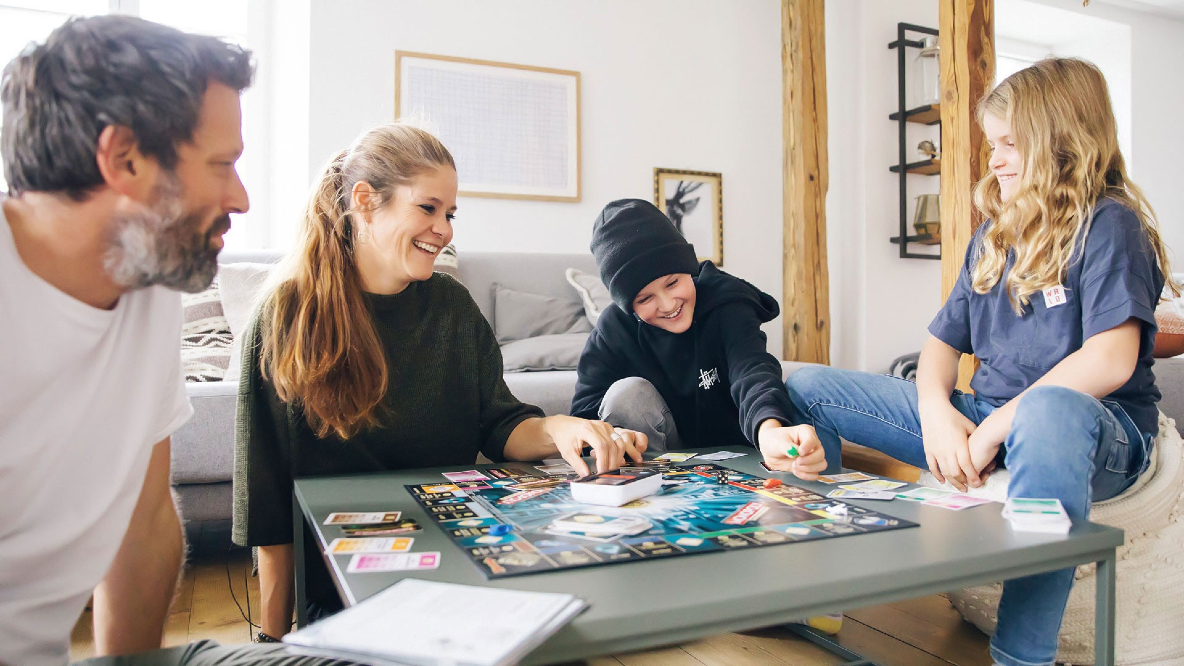 Melanie und ihre Familie spielen am Wohnzimmertisch ein Brettspiel.