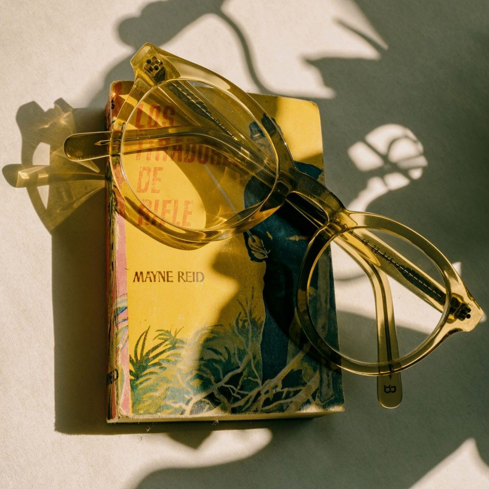Eine gelbe Brille liegt auf einem Buch mit gelbem Cover.