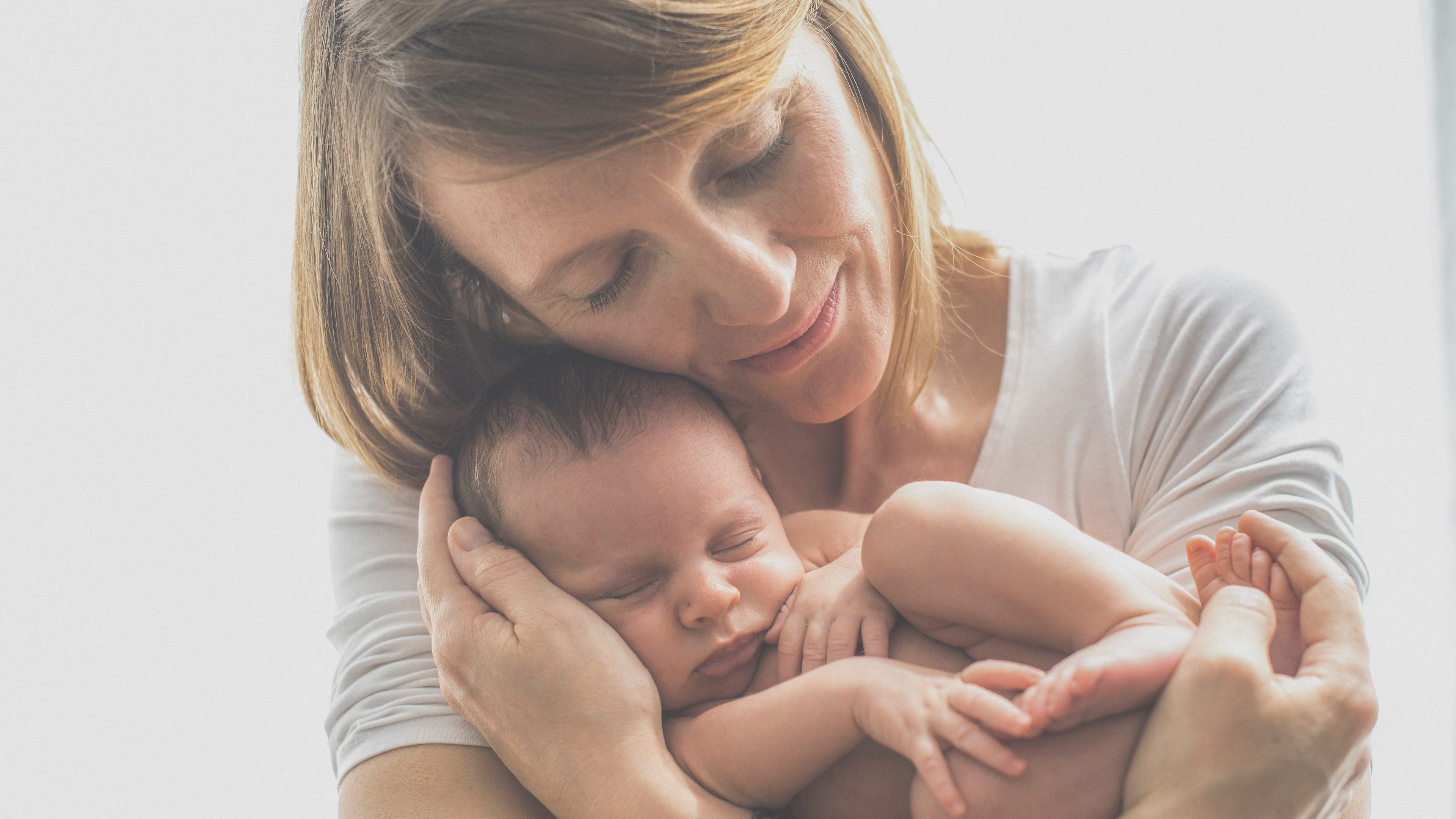 Eine Mutter hält ihr schlafendes Baby in den Armen.