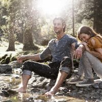 Ein junges Paar sitzt an einem Fluss und bespricht die anstehende Weltreise.