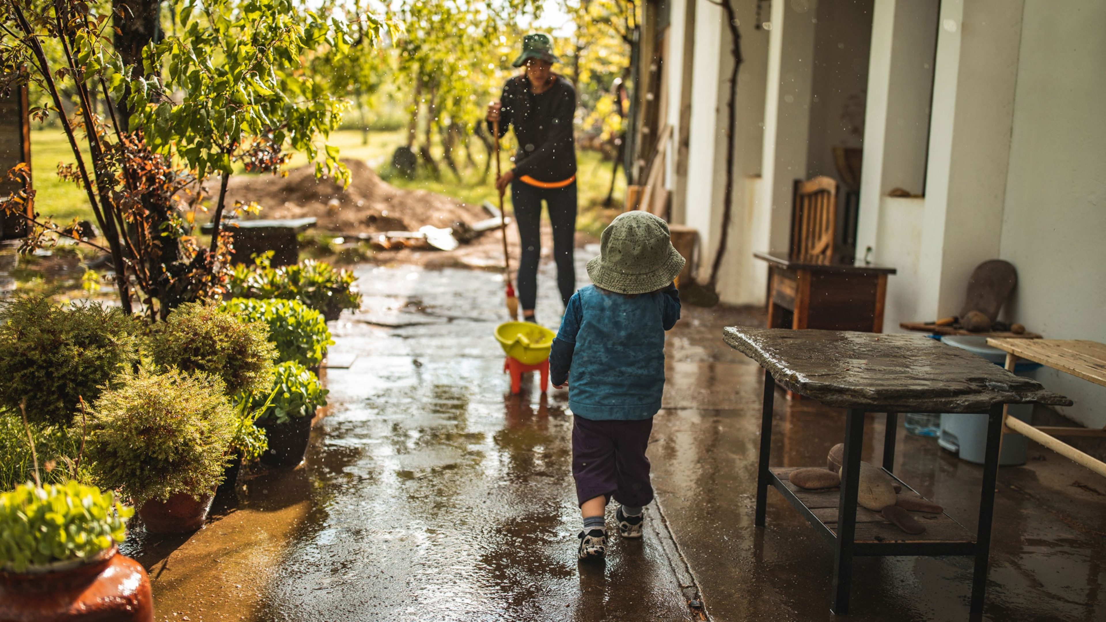 Eine Mutter räumt mit ihrem Sohn den Garten auf.