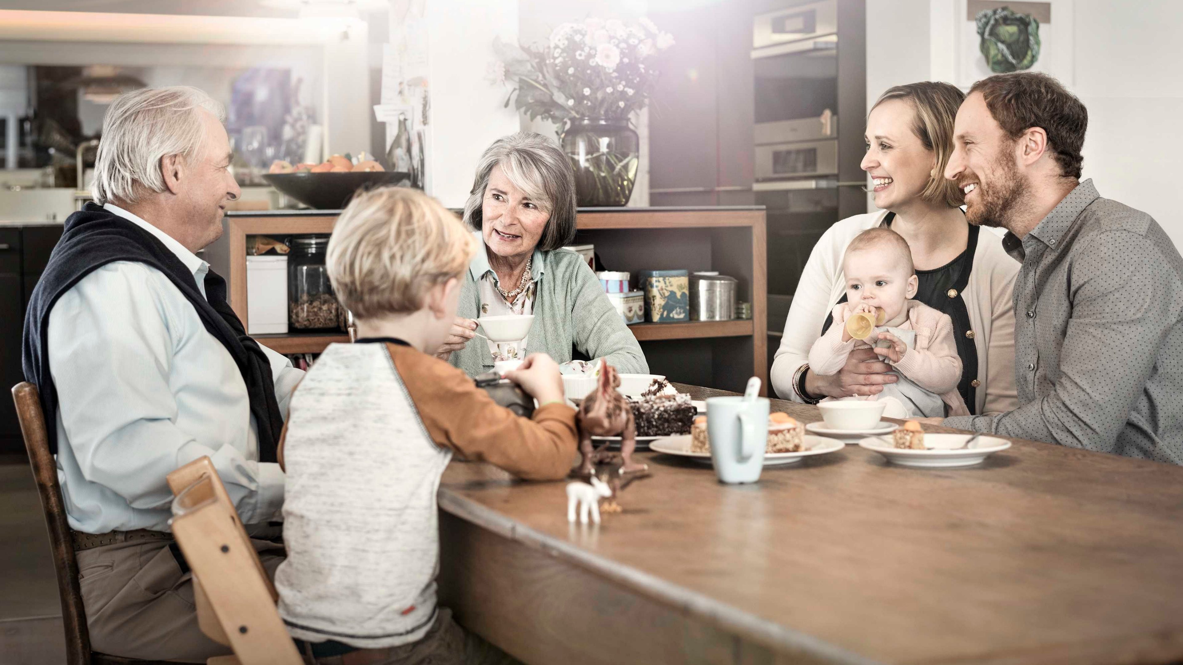 Familienmitglieder sitzen am Tisch und diskutieren finanzielle Vorsorge.