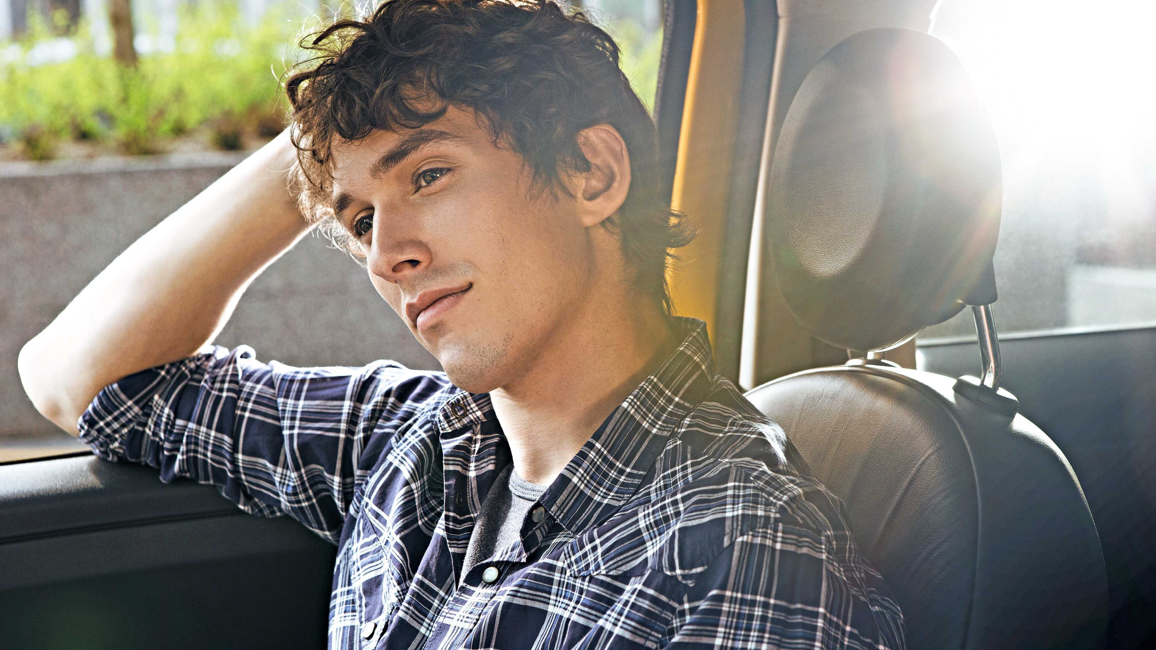 Ein junger Mann sitzt im Beifahrersitz eines Autos.