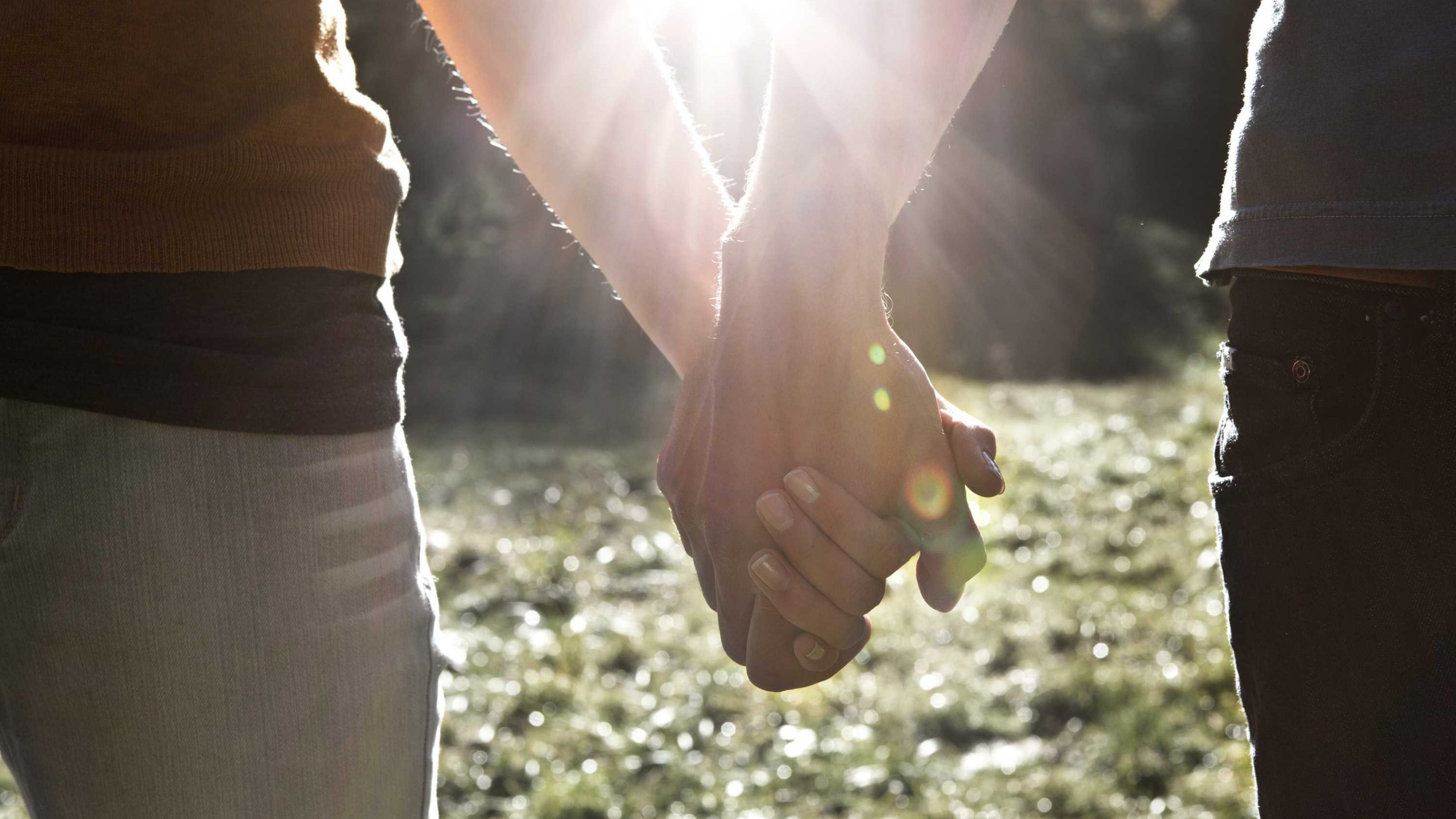 Ein Paar spaziert Hand in Hand in der Natur.
