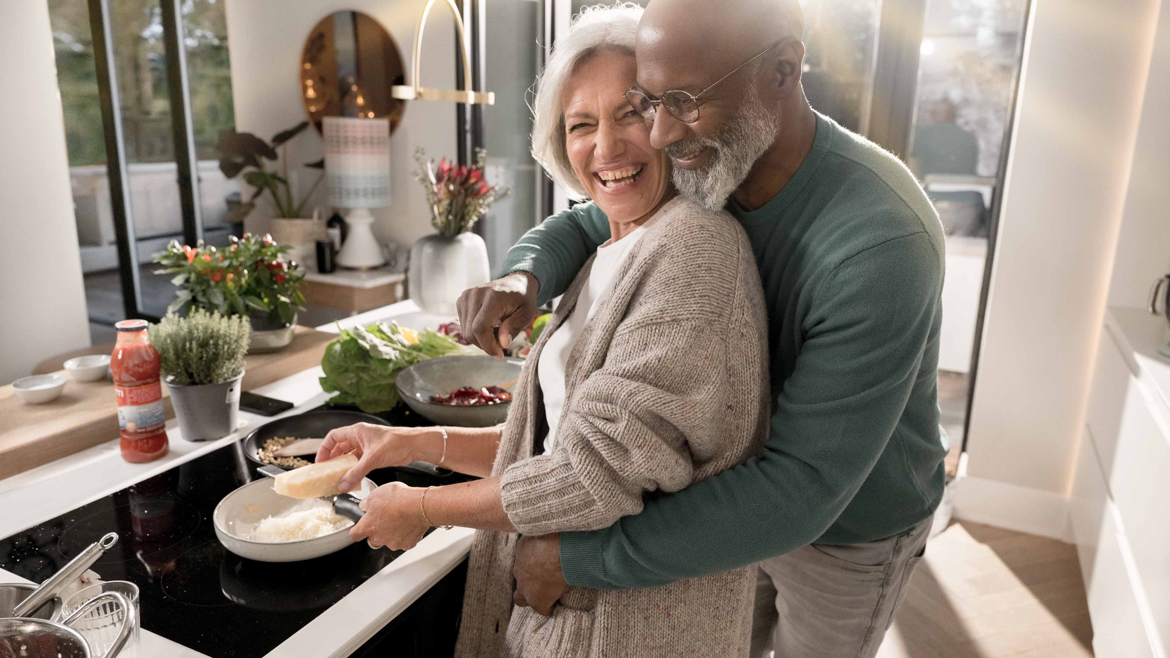 Ältere Frau und älterer Mann kochen im Eigenheim