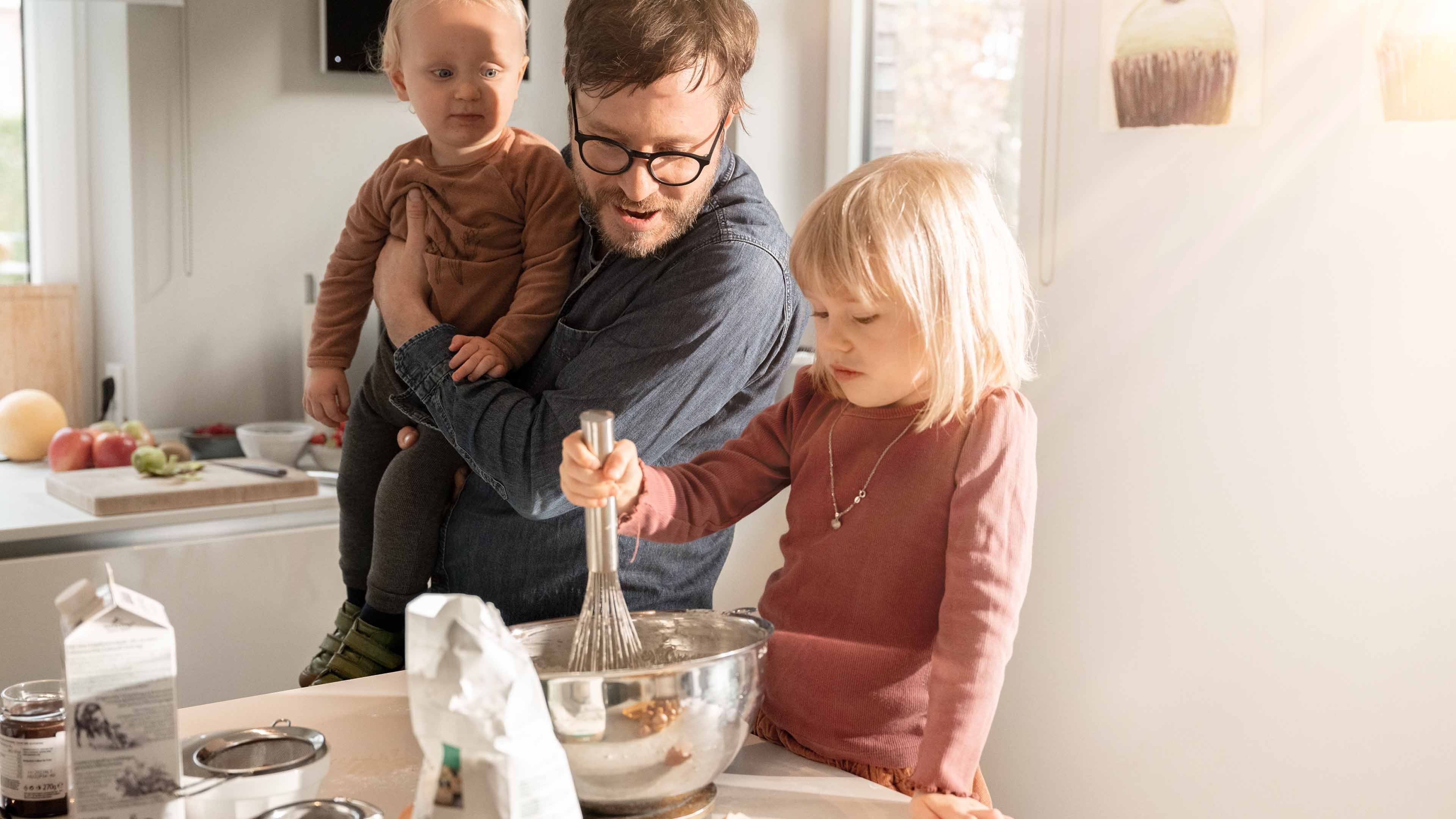 Vater backt Kuchen mit seinen zwei Kindern