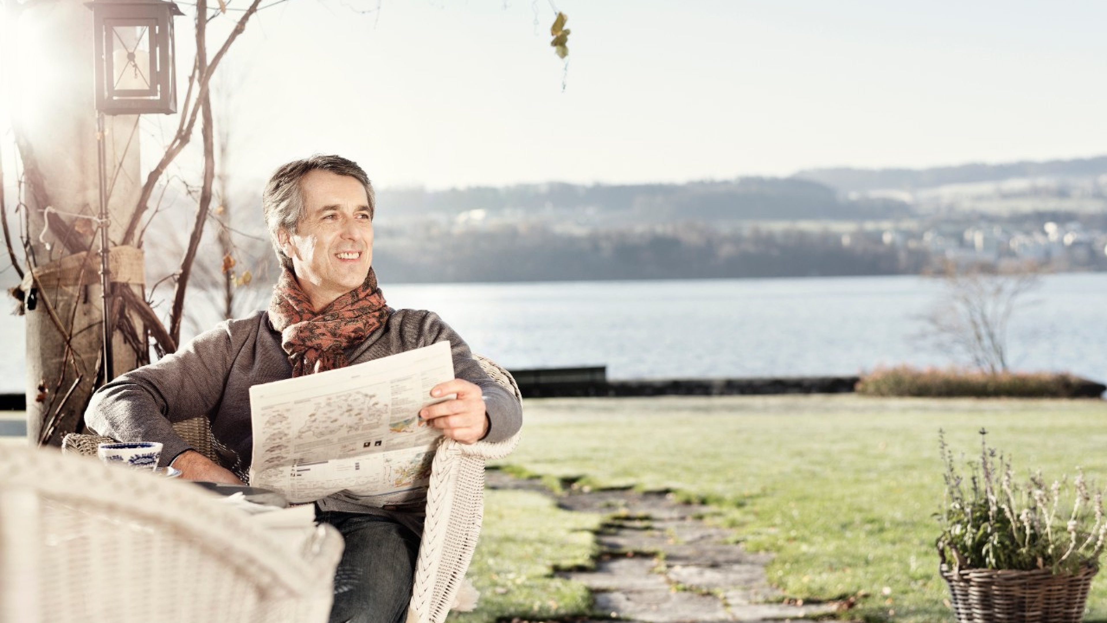 Mann sitzt mit Zeitung im Garten