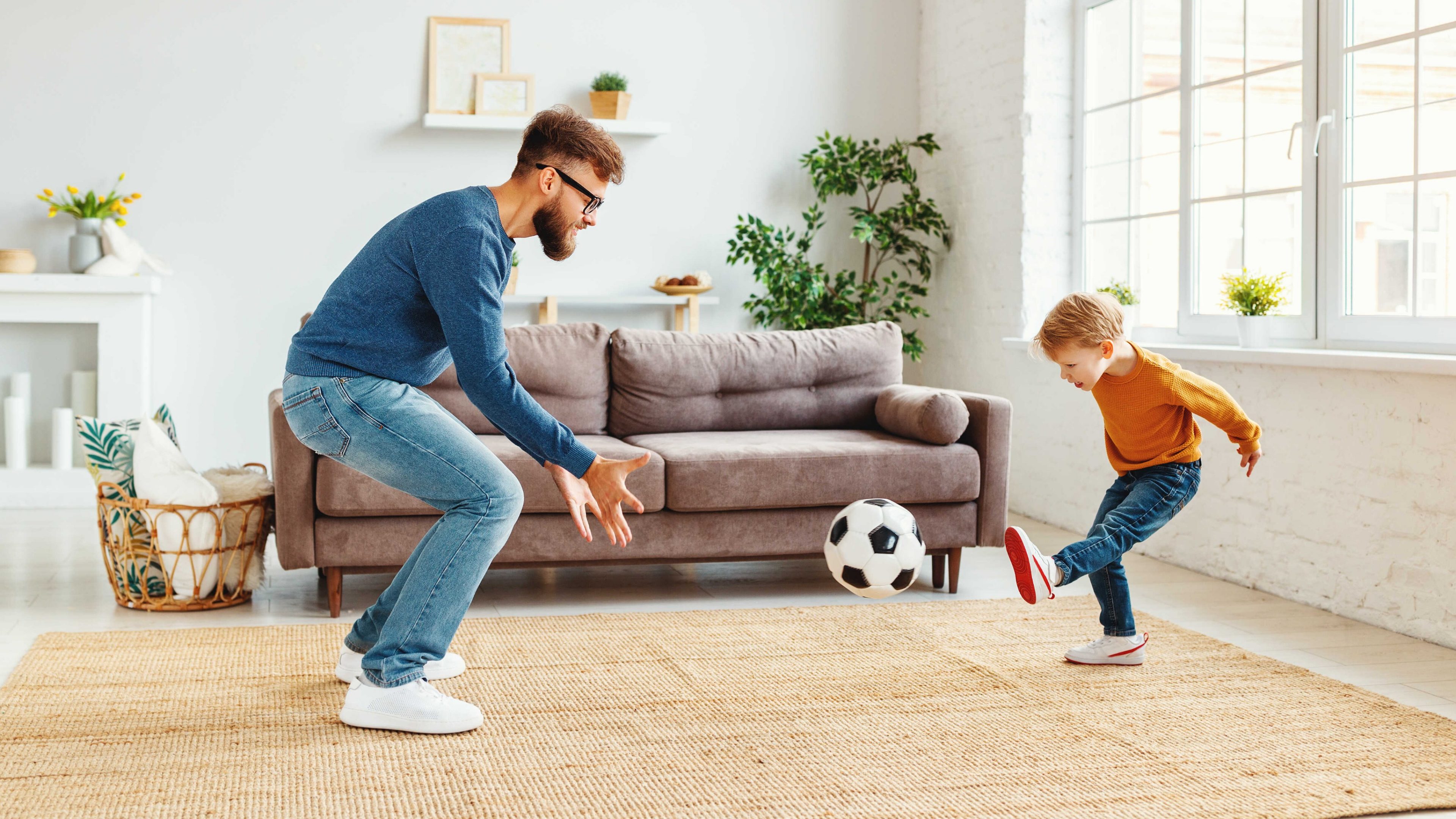 Vater und Sohn spielen Fussball im Eigenheim.