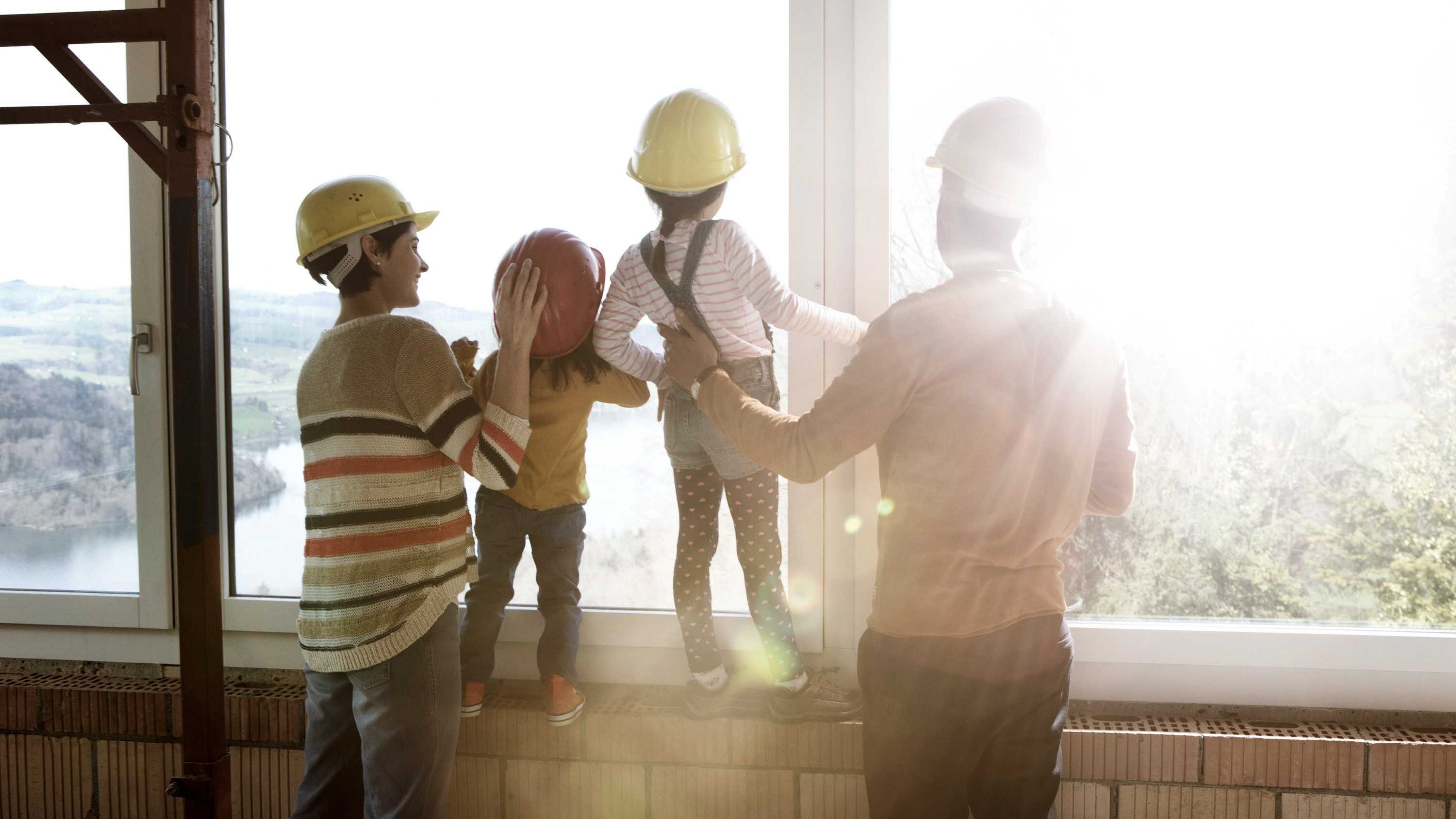 Eine Familie steht im Rohbau des neuen Eigenheims.