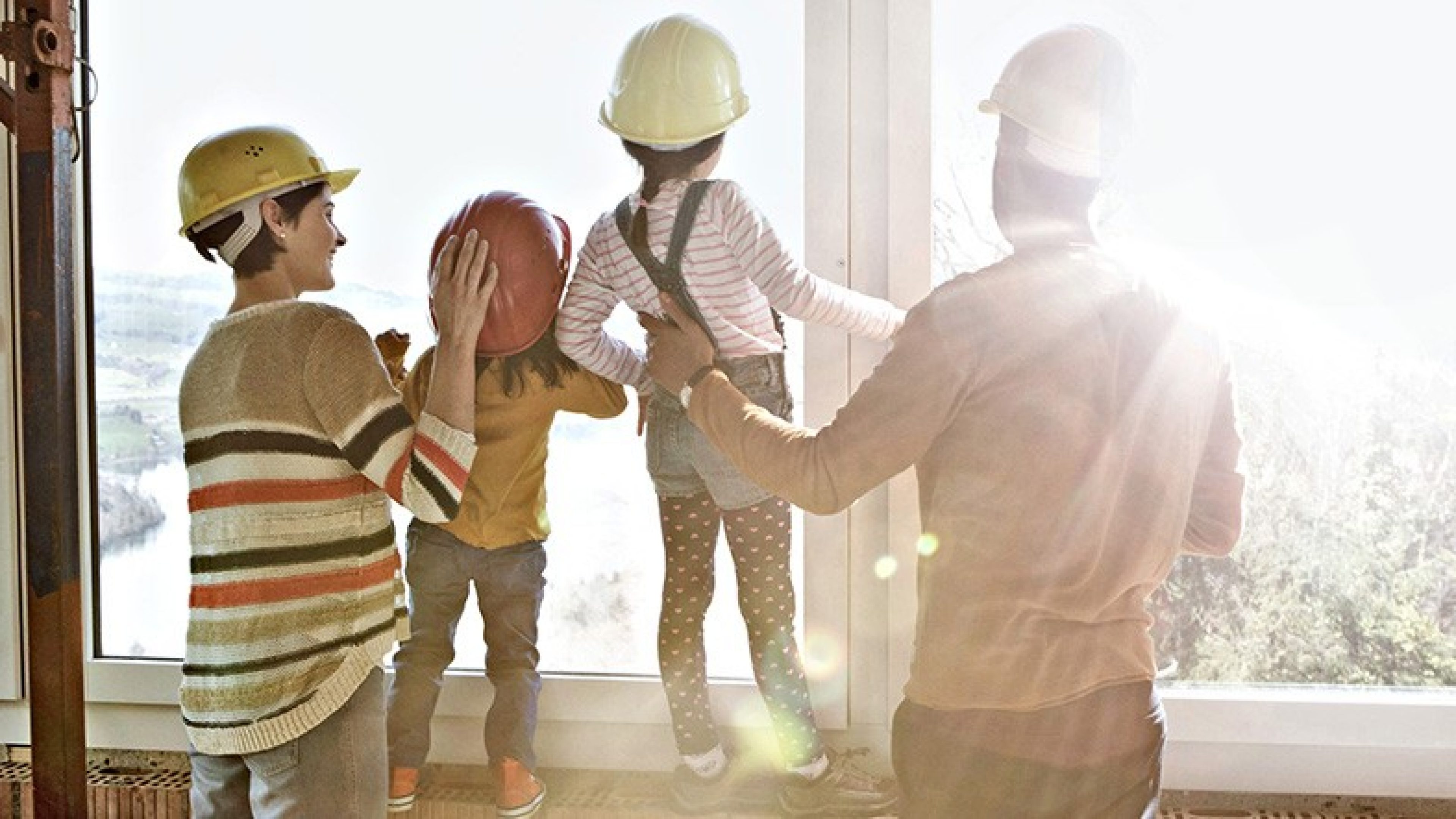 Familie schaut aus dem Fenster ihres zukünftigen Eigenheims