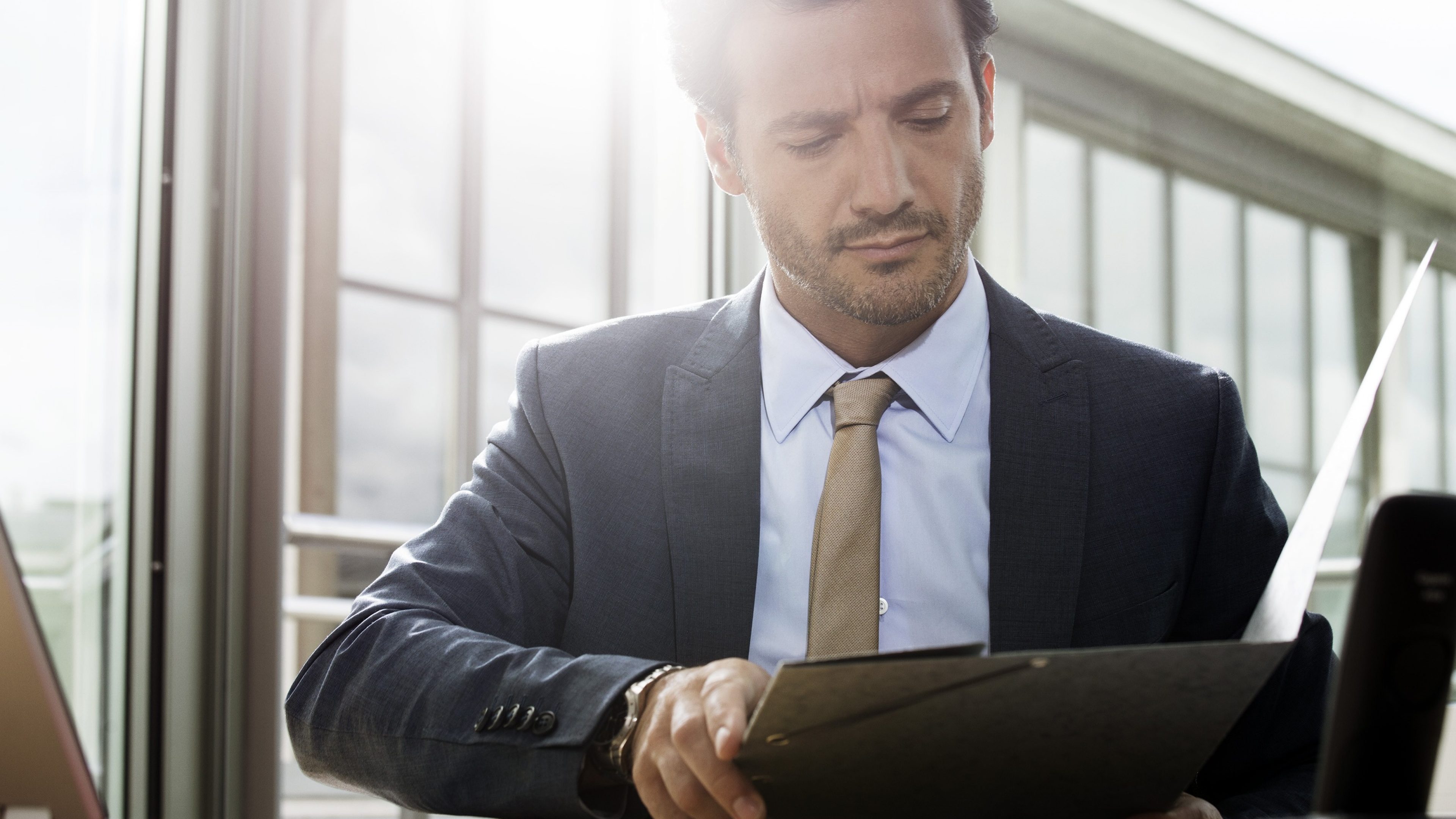 Ein Mann überlegt im Büro, wie er für sein Eigenheim ansparen und es finanzieren kann.