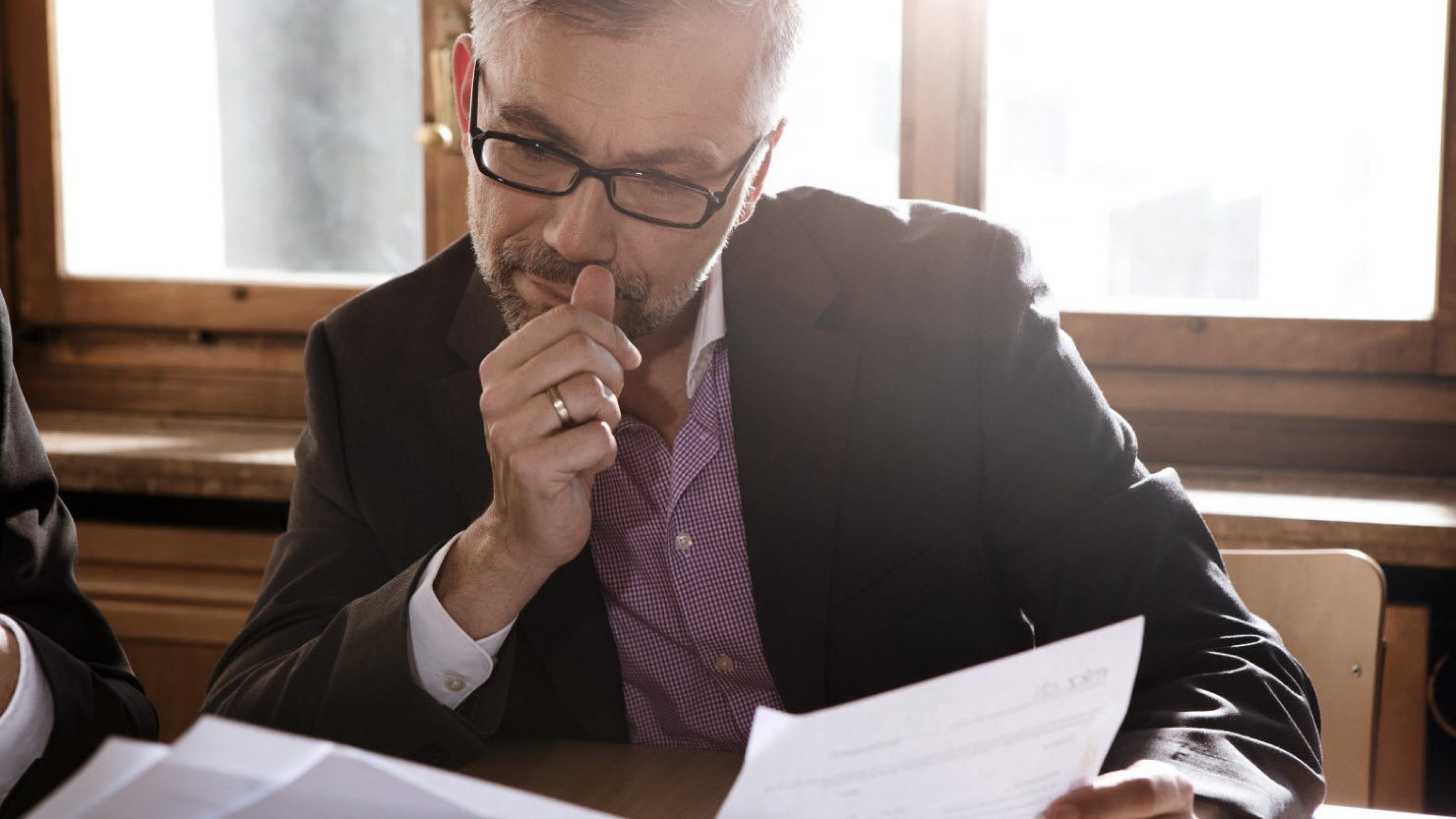 Ein Mann studiert im Büro Unterlagen zum Suchen und Kaufen von Immobilien.