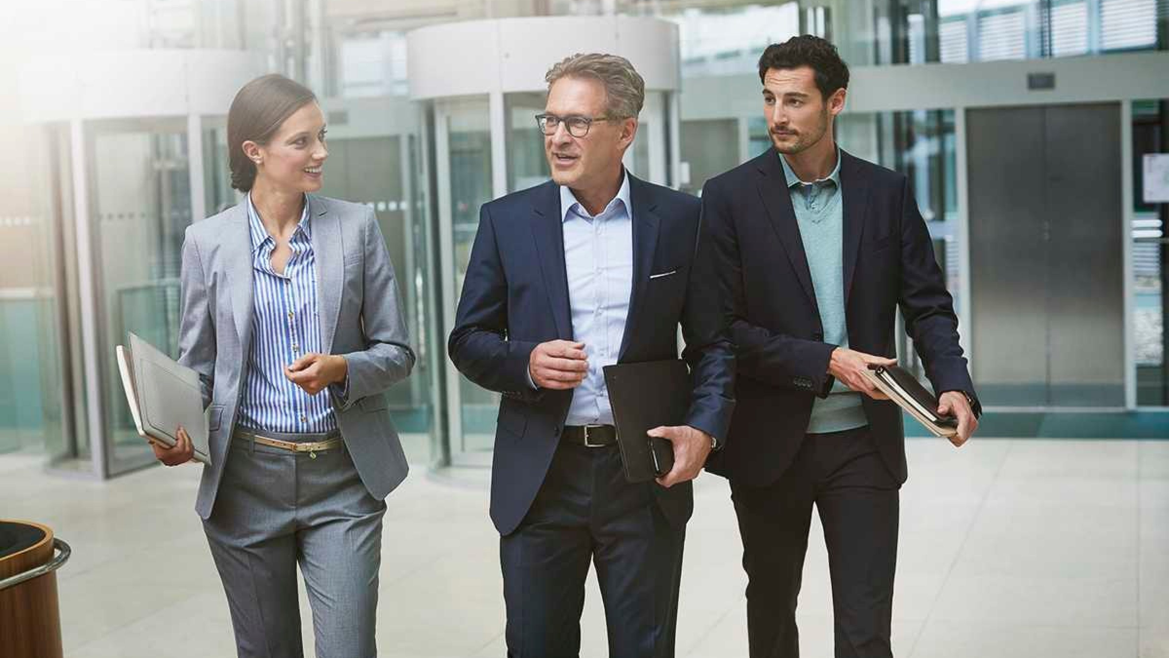 Geschäftskollegen verlassen das Bürogebäude und besprechen Karrierethemen.
