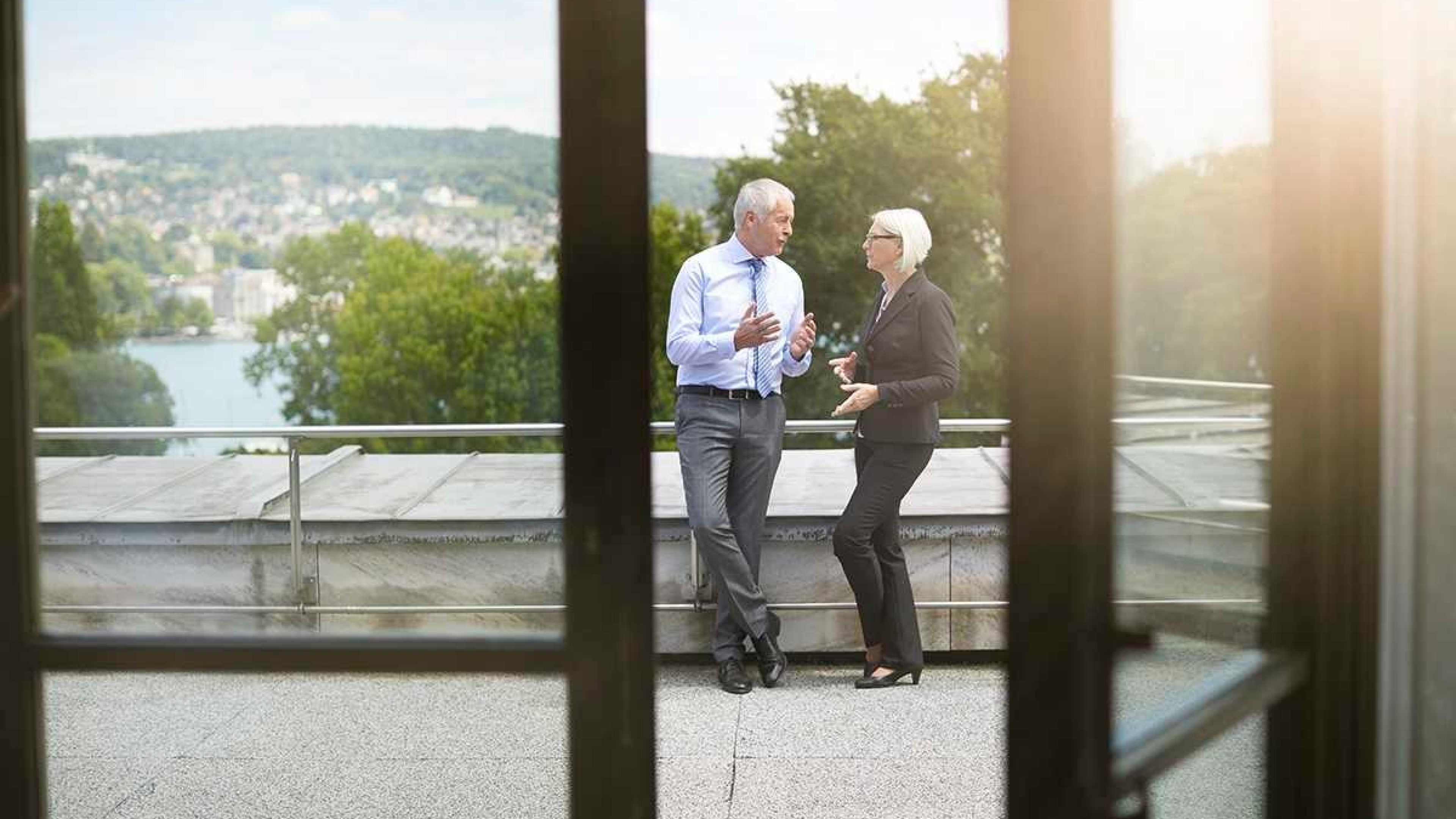 Zwei Arbeitskollegen stehen auf der Büroterasse und besprechen Steuerersparnis.