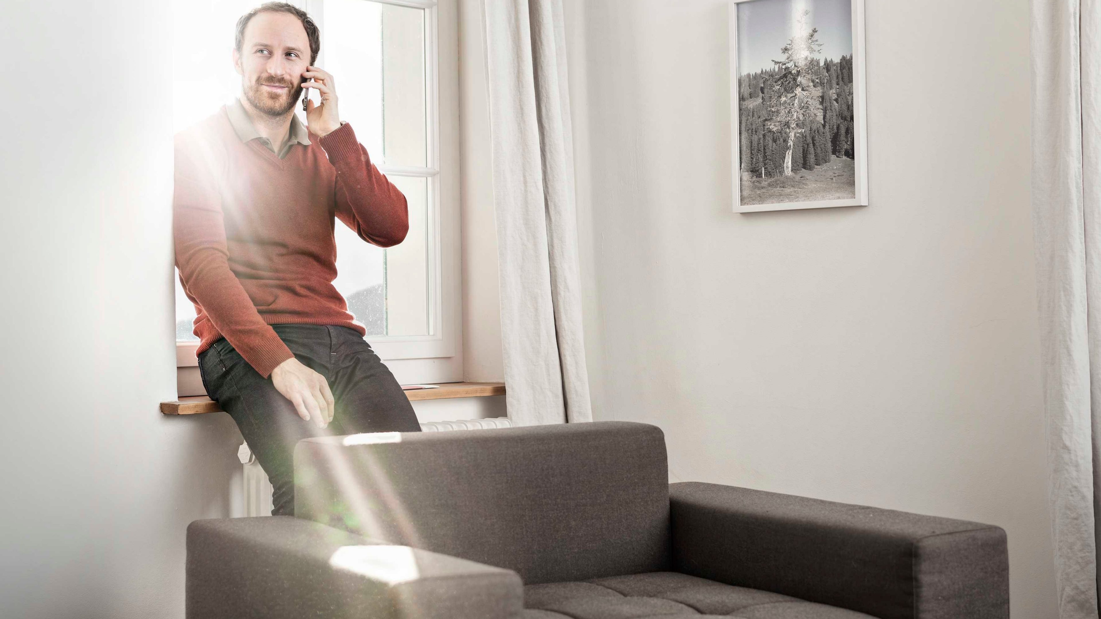 Mann lässt sich zuhause am Mobiltelefon zum Thema Risikoschutz beraten.