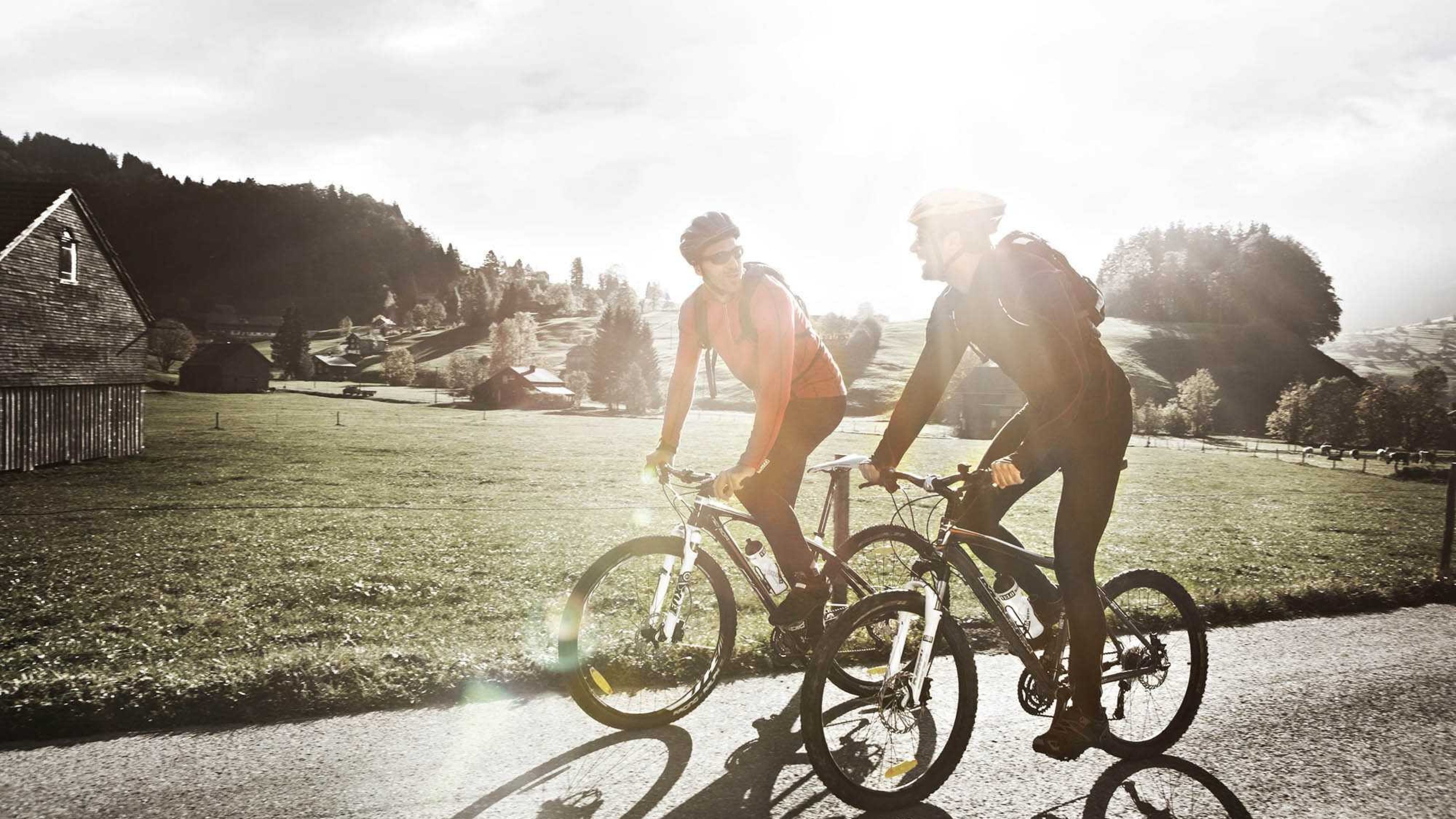 Zwei Radfahrer besprechen Ihre Krankenkasse während der Fahrt.