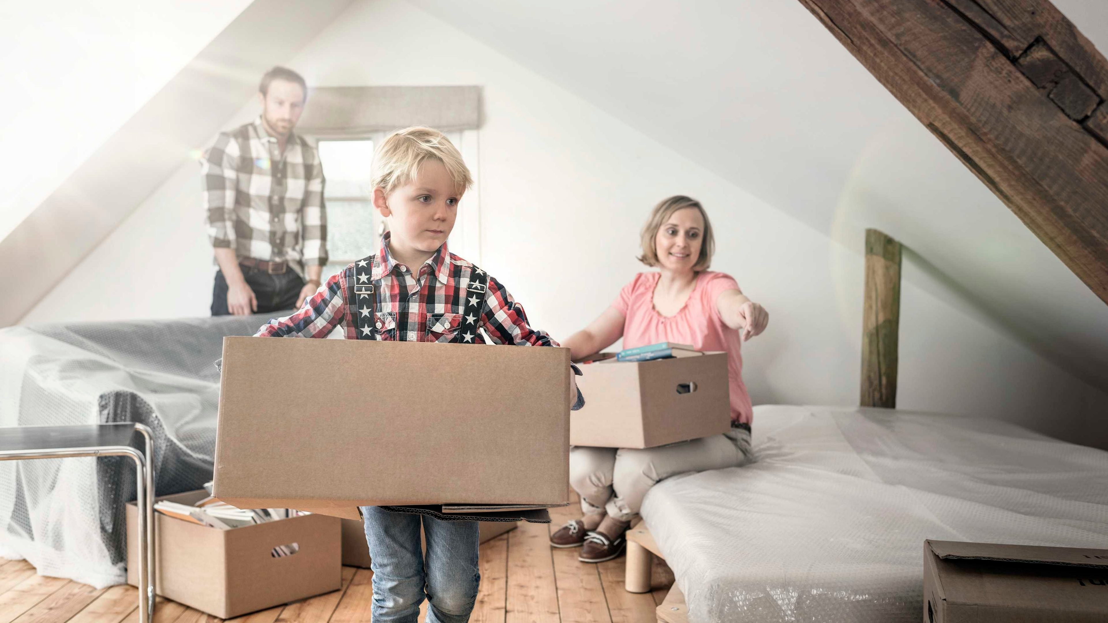 Eltern und Sohn packen Kisten im neuen Eigenheim aus.