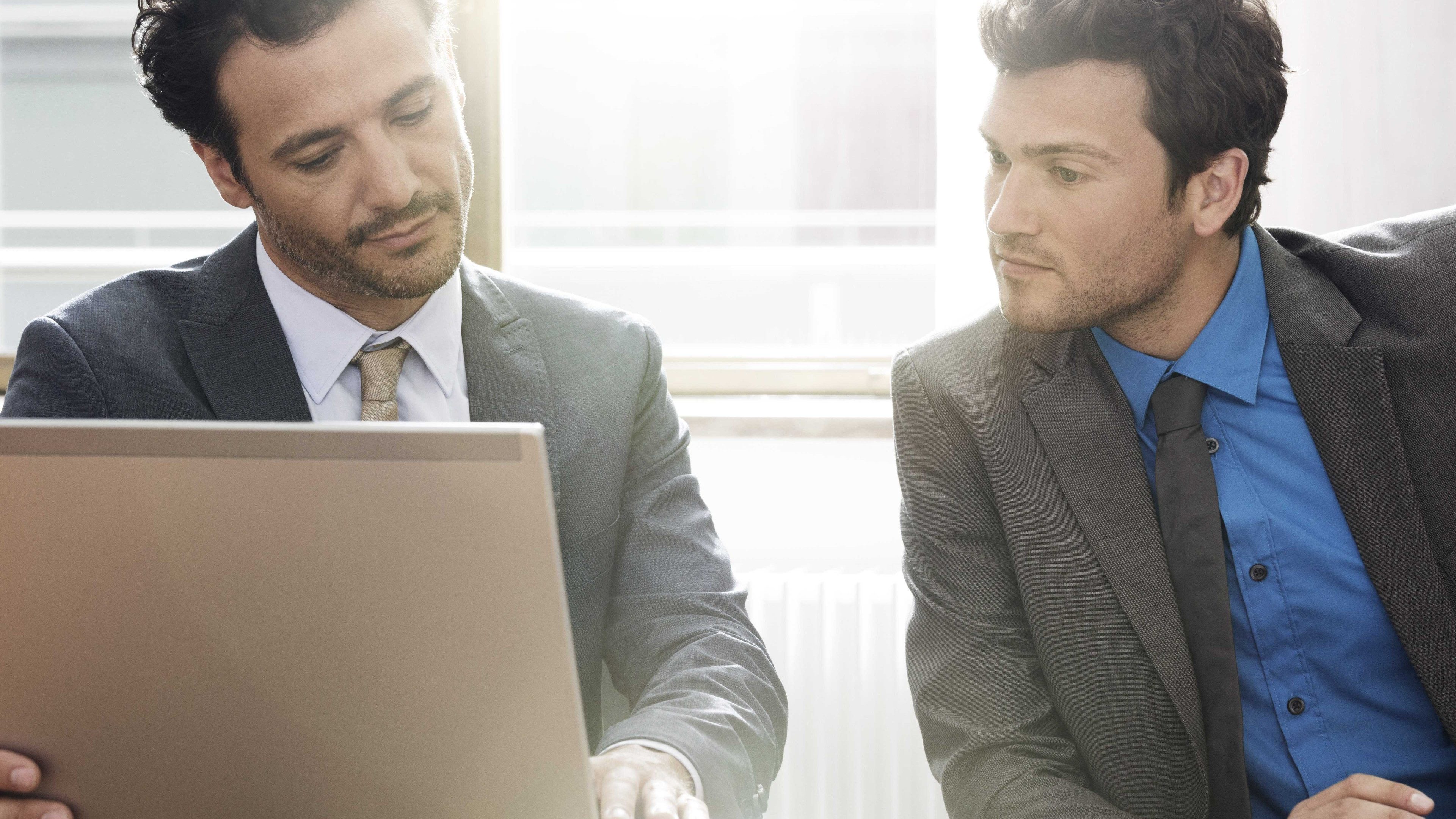 Arbeitskollegen sitzen im Büro und machen den Vorsorgecheck am Computer.