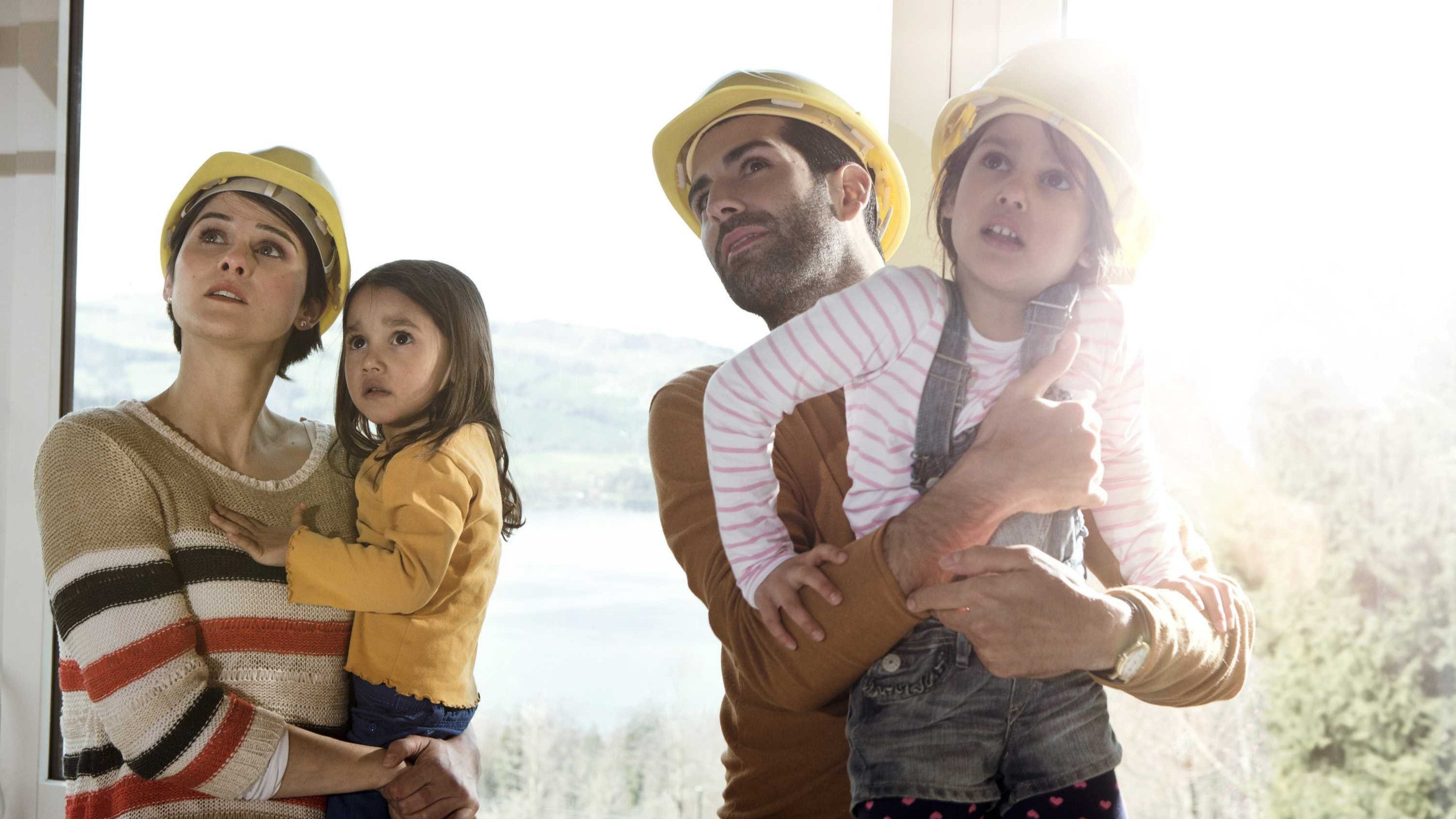 Eltern mit zwei kleinen Kindern begutachten das neue Eigenheim.