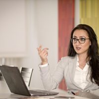 Frau mit Laptop vor sich im Business-Outfit