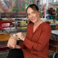 Martina Gantenbein wirft eine Münze in eine Spardose.