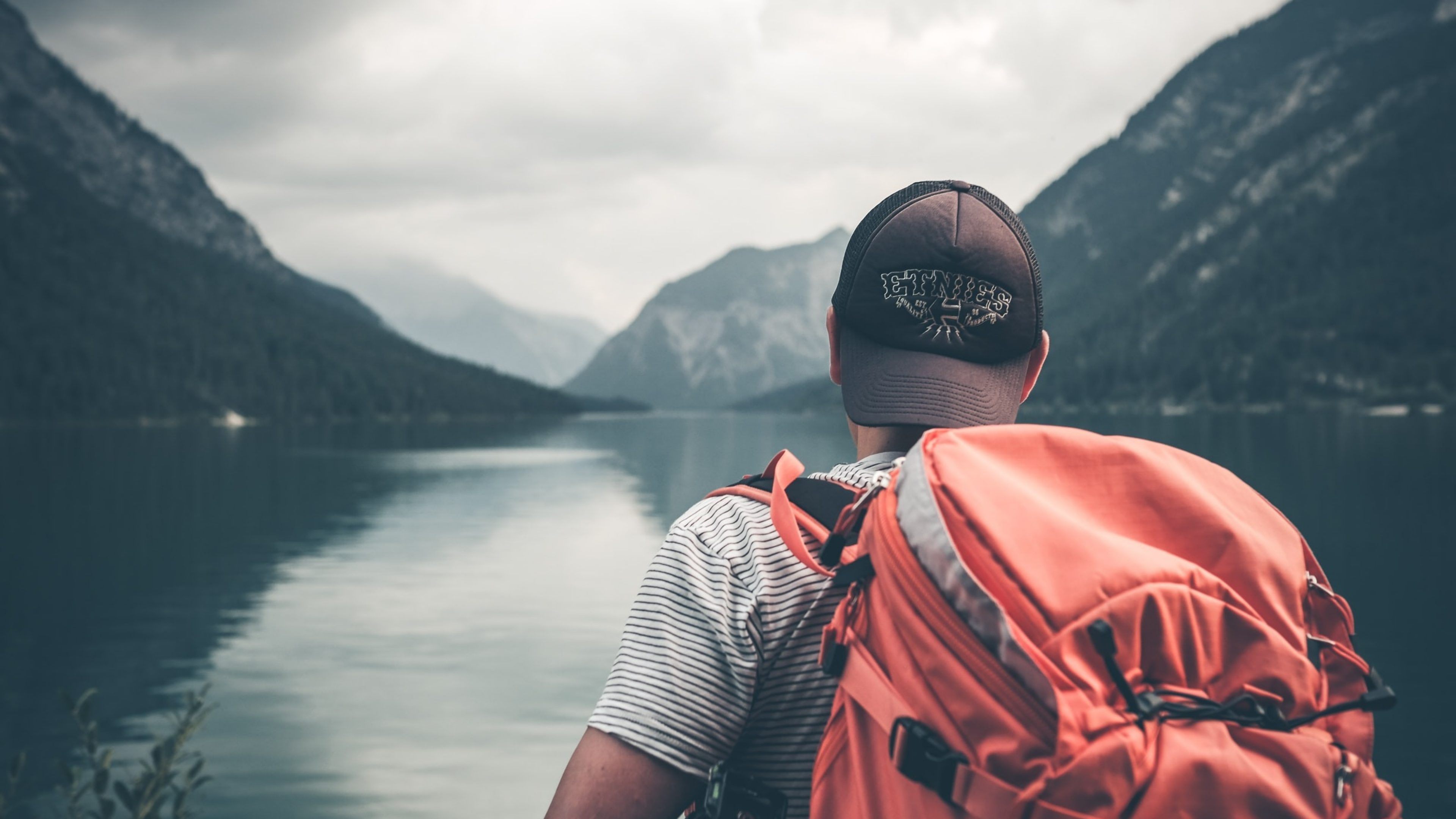 Ein Wanderer blickt auf einen See.