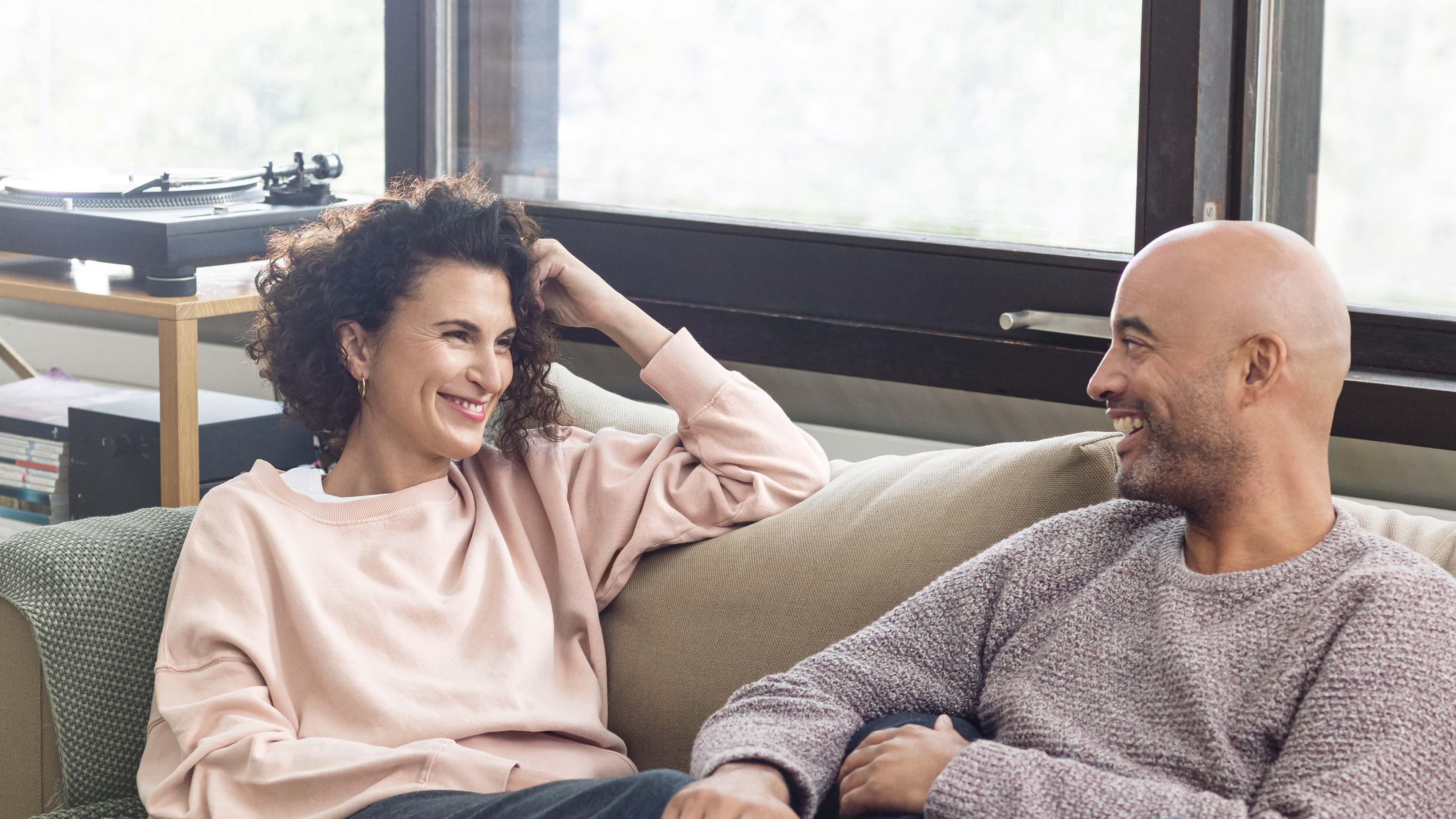 Zwei Personen sitzen auf einem Sofa und unterhalten sich