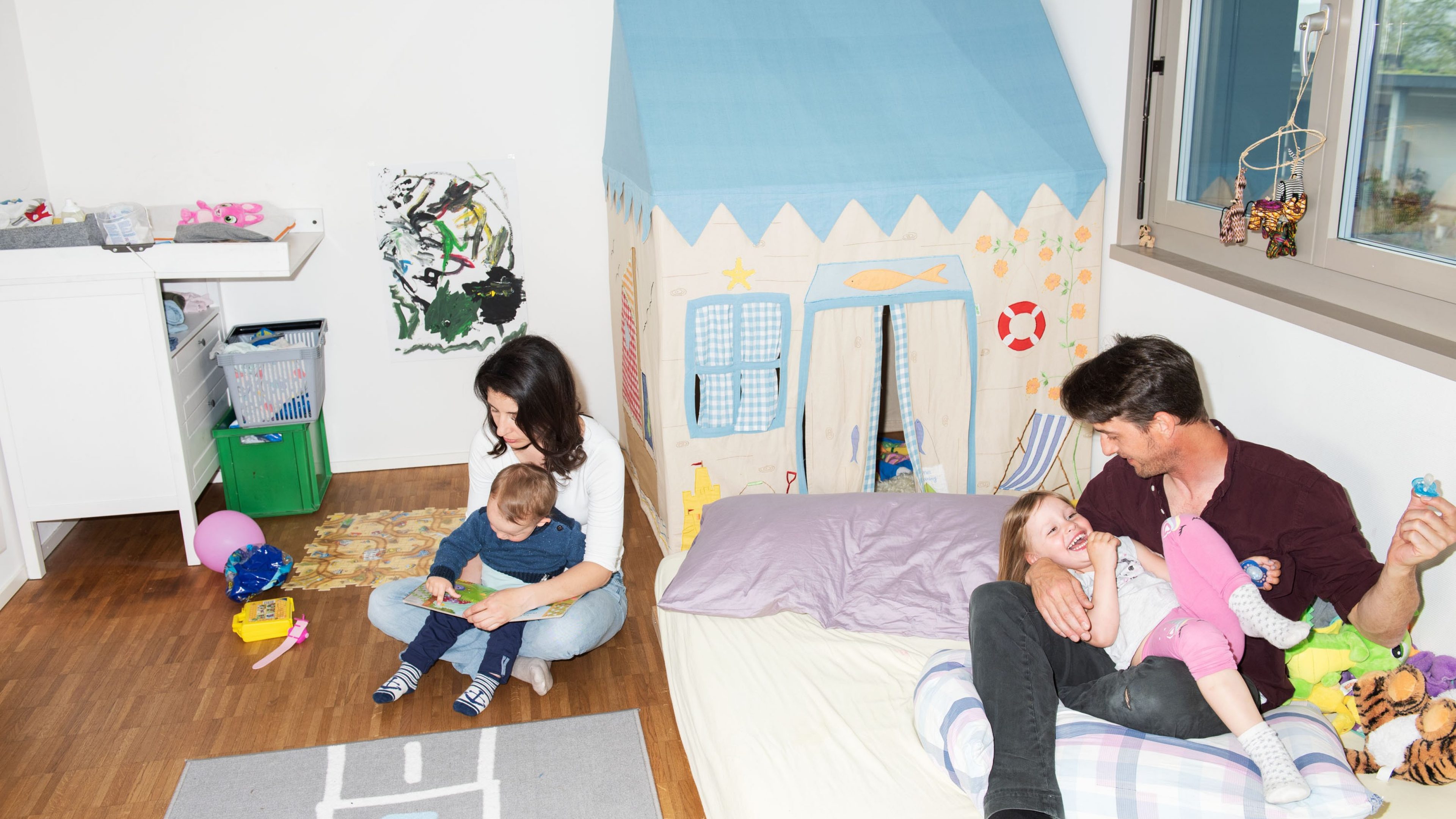 Eltern spielen mit ihren zwei Kindern im Kinderzimmer.
